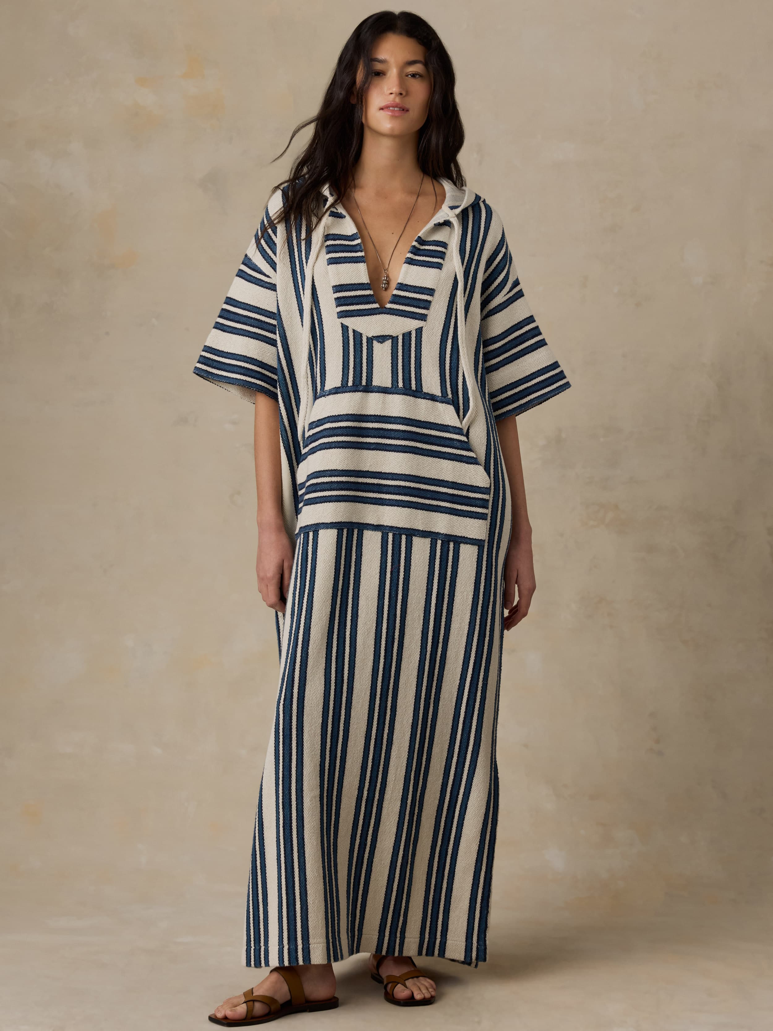Woman wearing a blue and white striped dress against a beige background