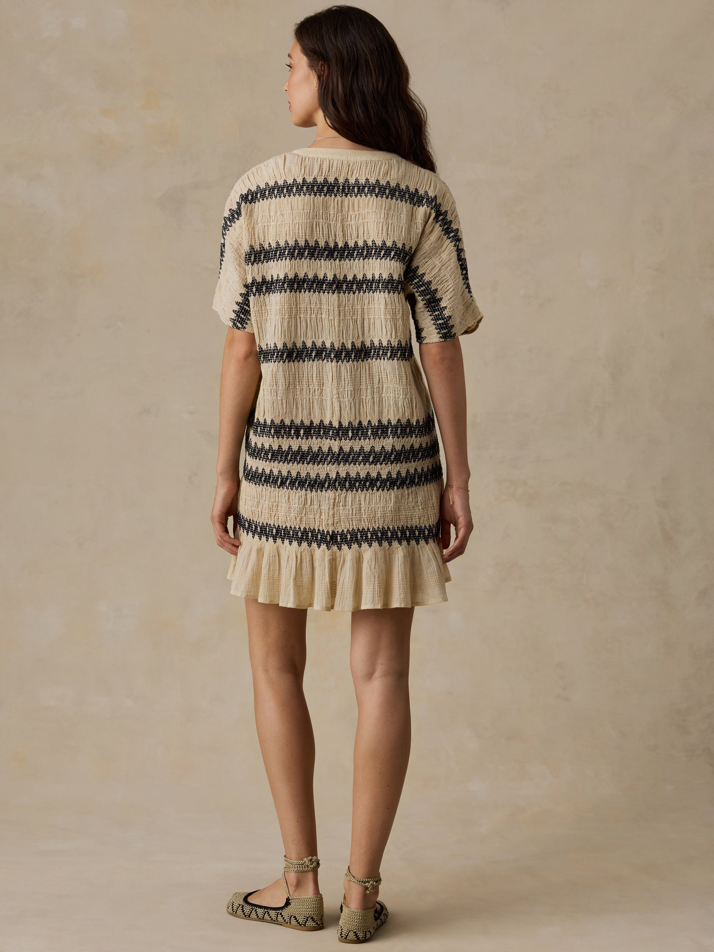 Woman wearing a beige and black striped dress against a beige background