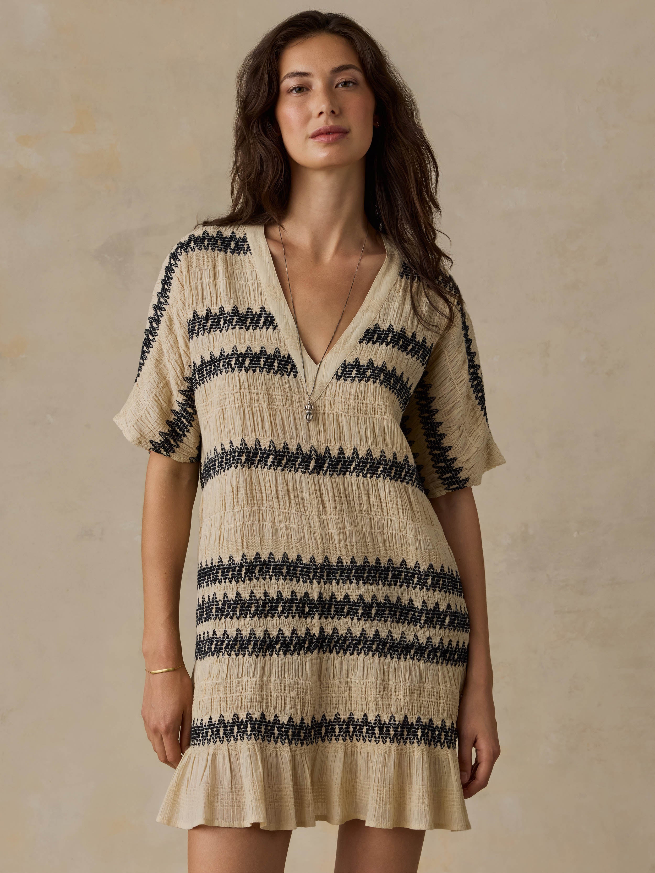 Woman wearing a beige and black striped dress against a beige background