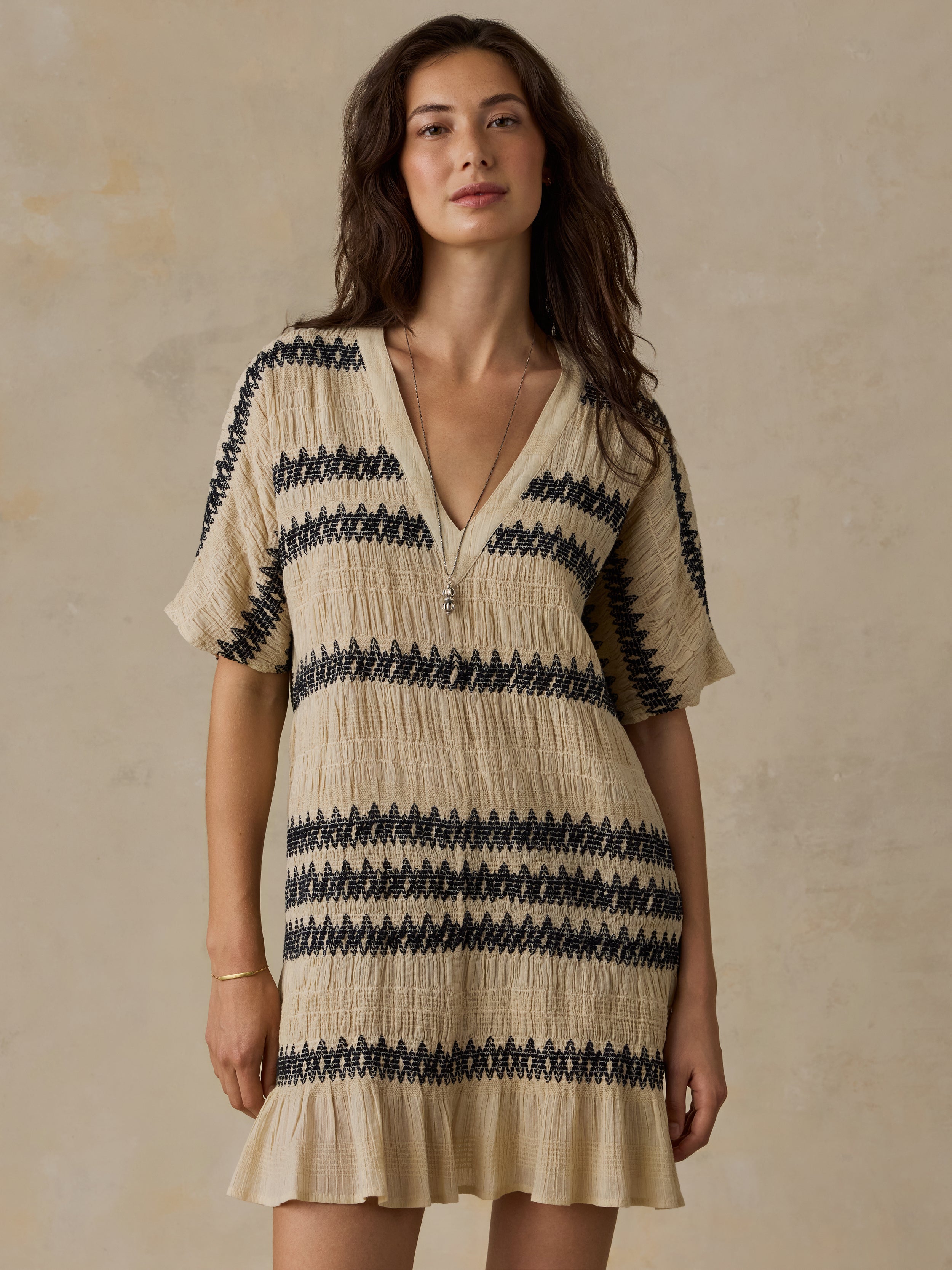 Woman wearing a beige and black striped dress against a beige background