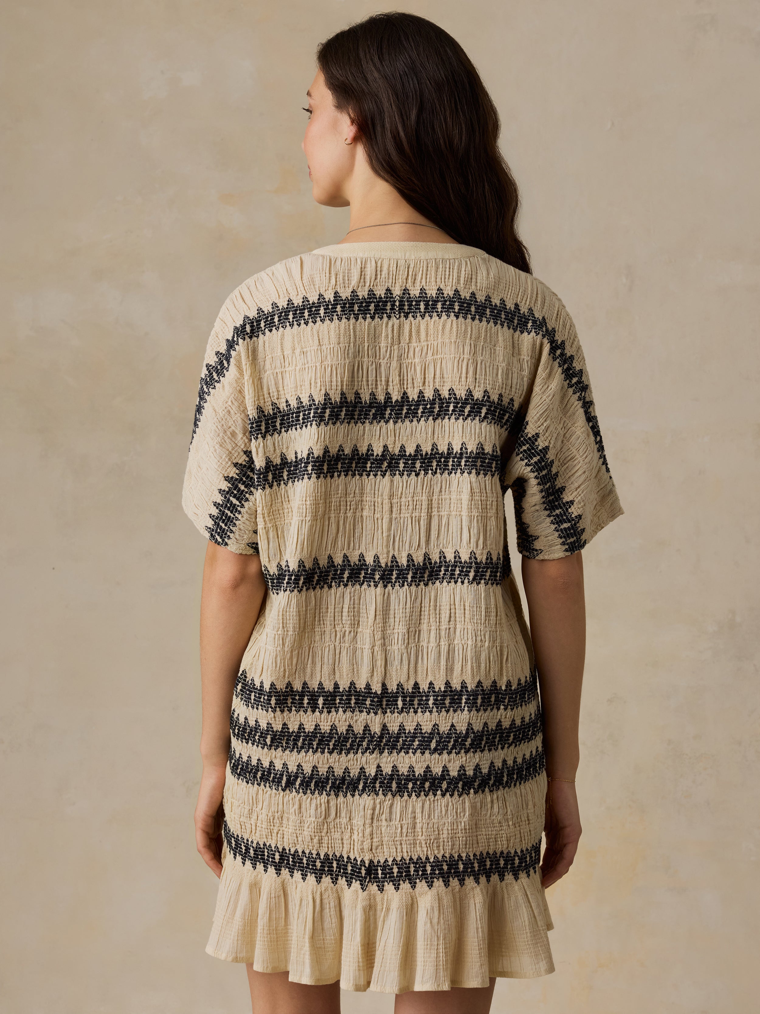 Woman wearing a beige and black striped dress against a beige background