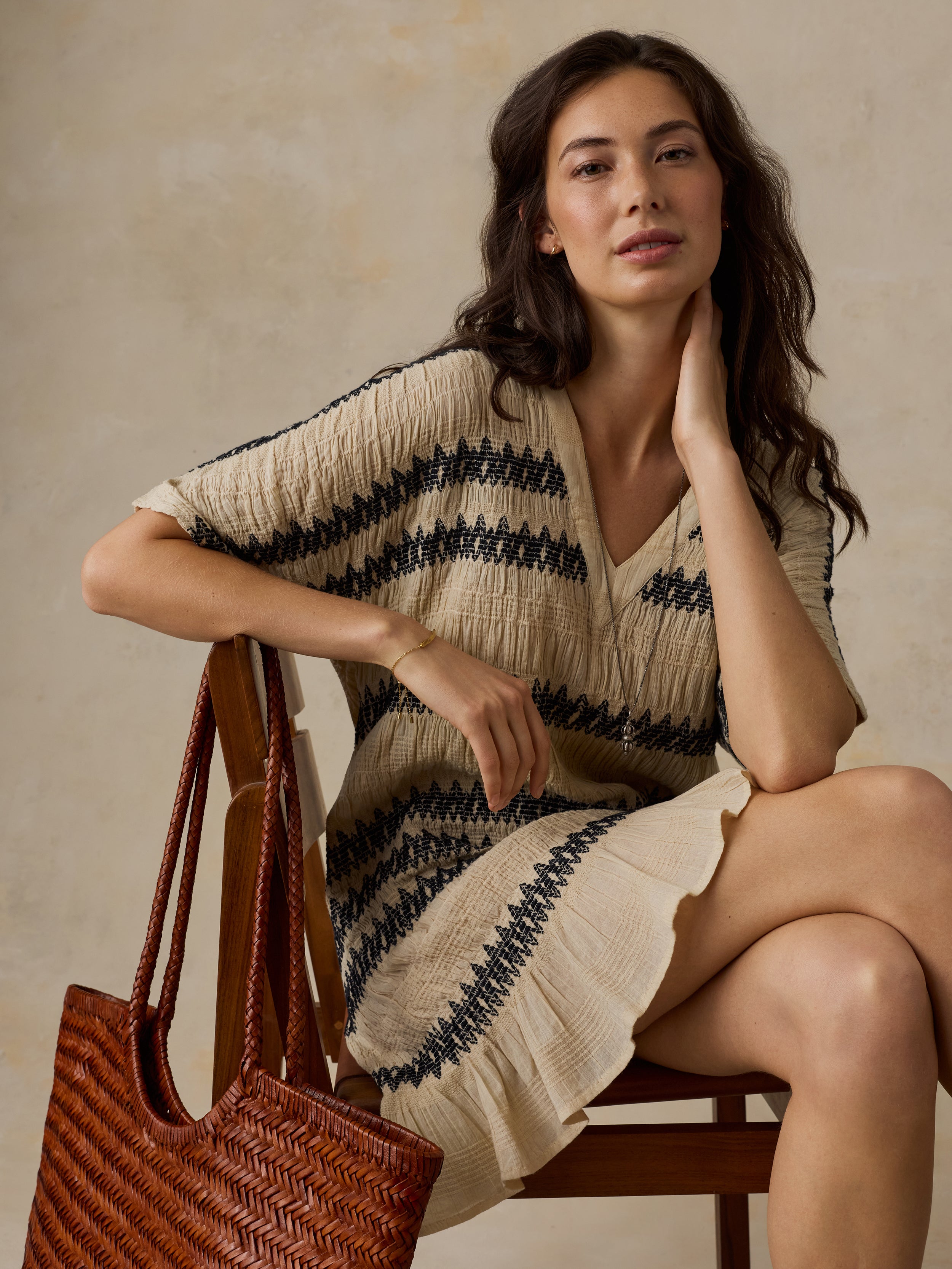 Woman wearing a beige and black striped dress against a beige background