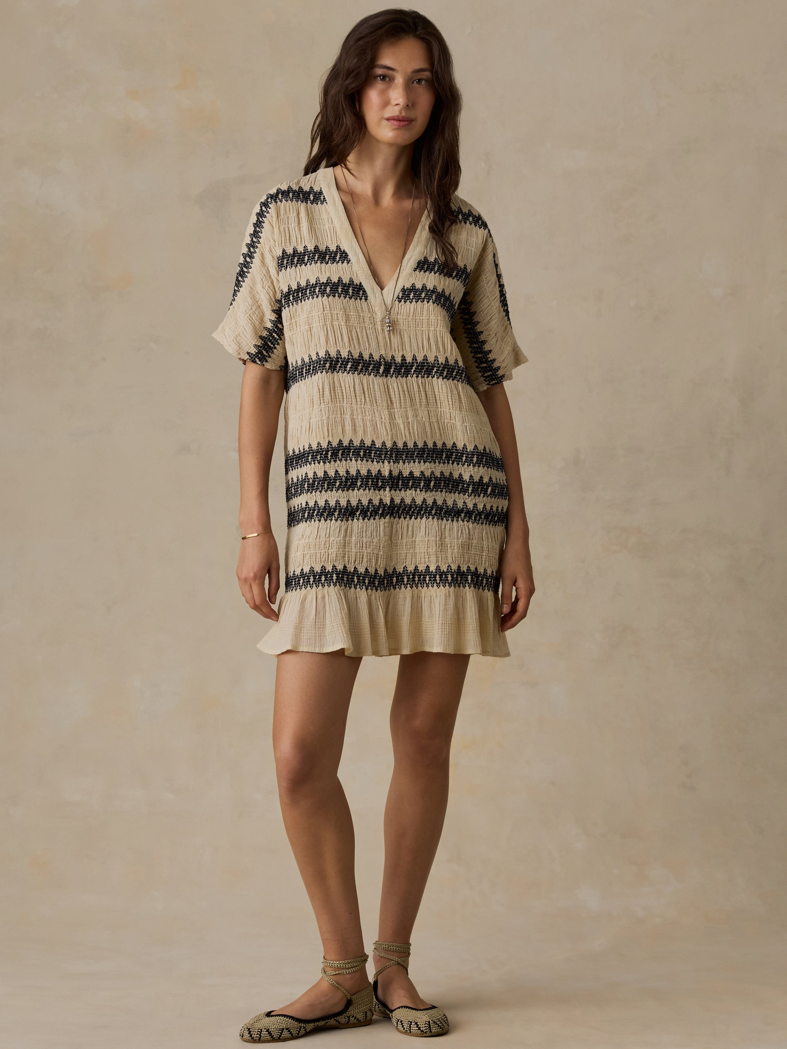 Woman wearing a beige and black striped dress against a beige background