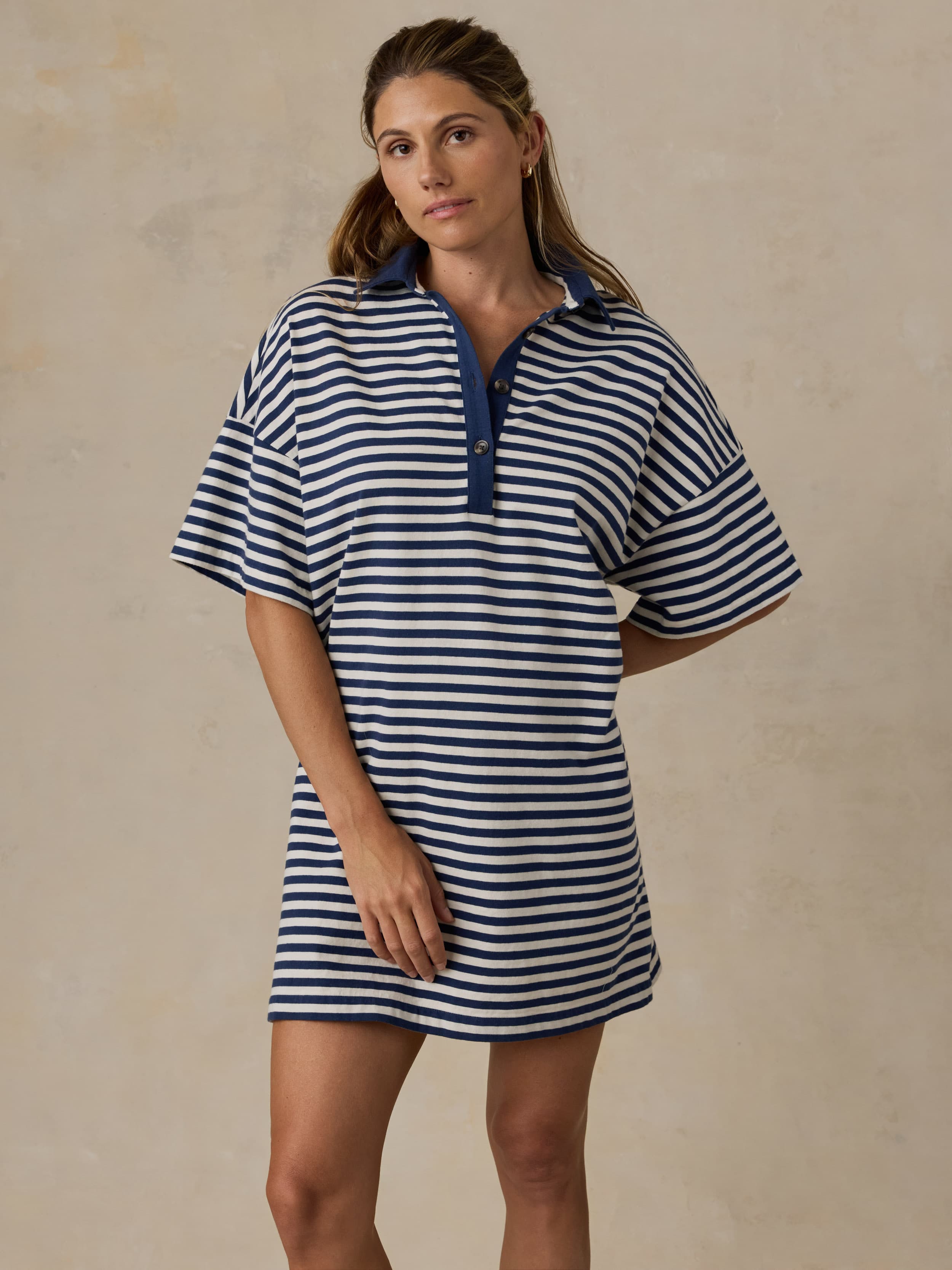 Woman wearing a blue and white striped dress against a beige background