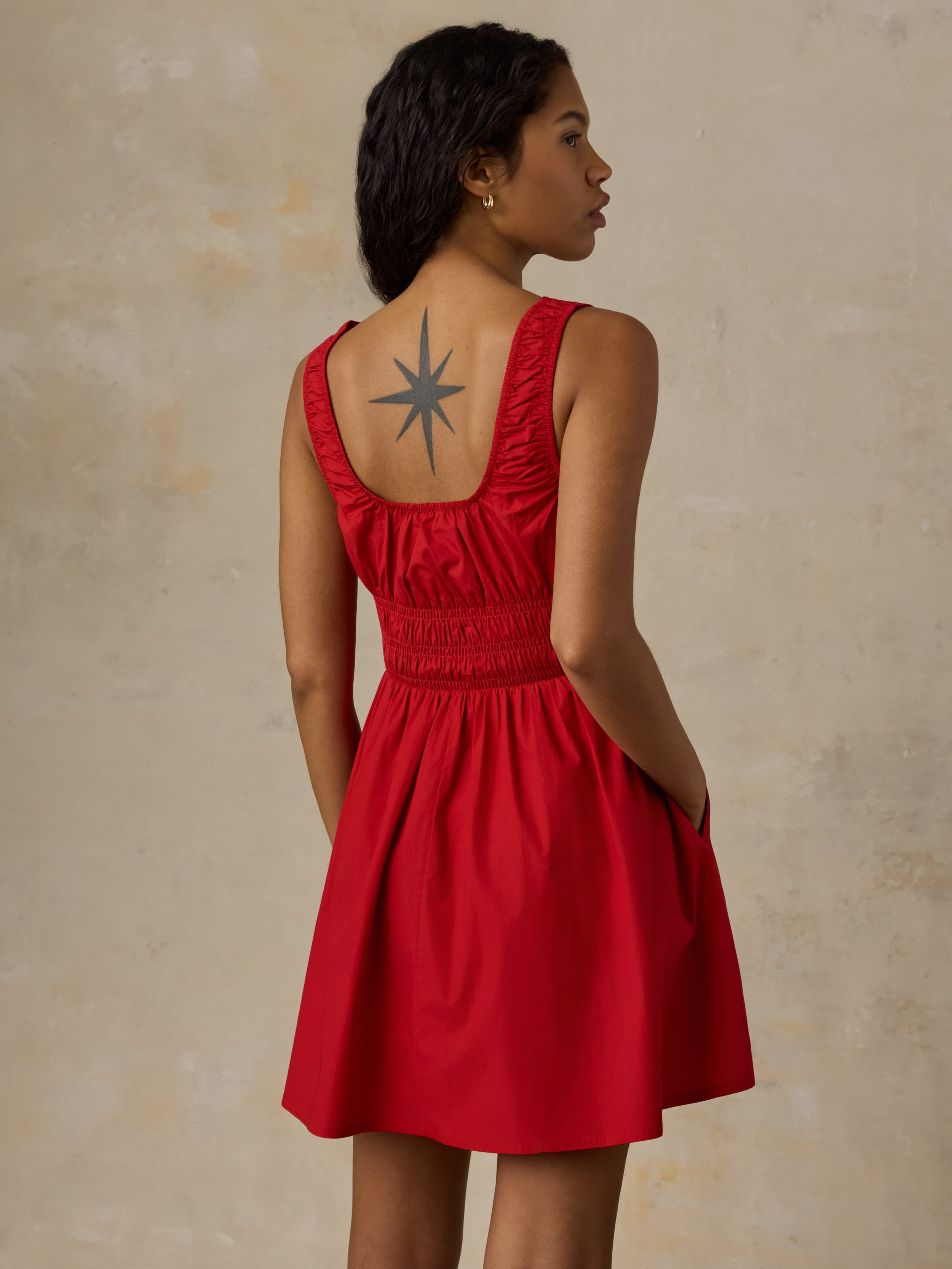 Woman wearing a red dress with against a beige background