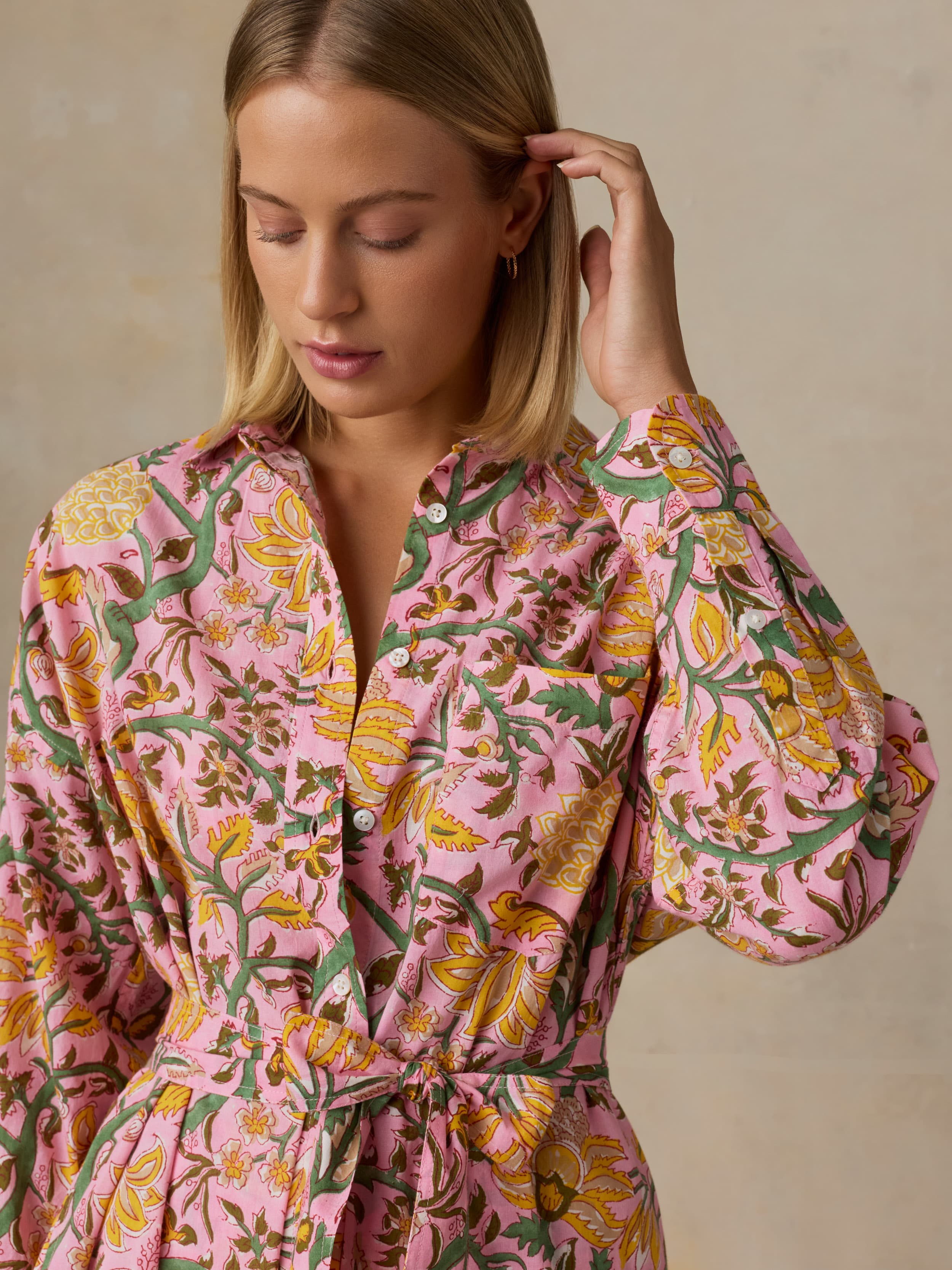 Woman wearing a pink floral dress against a beige background