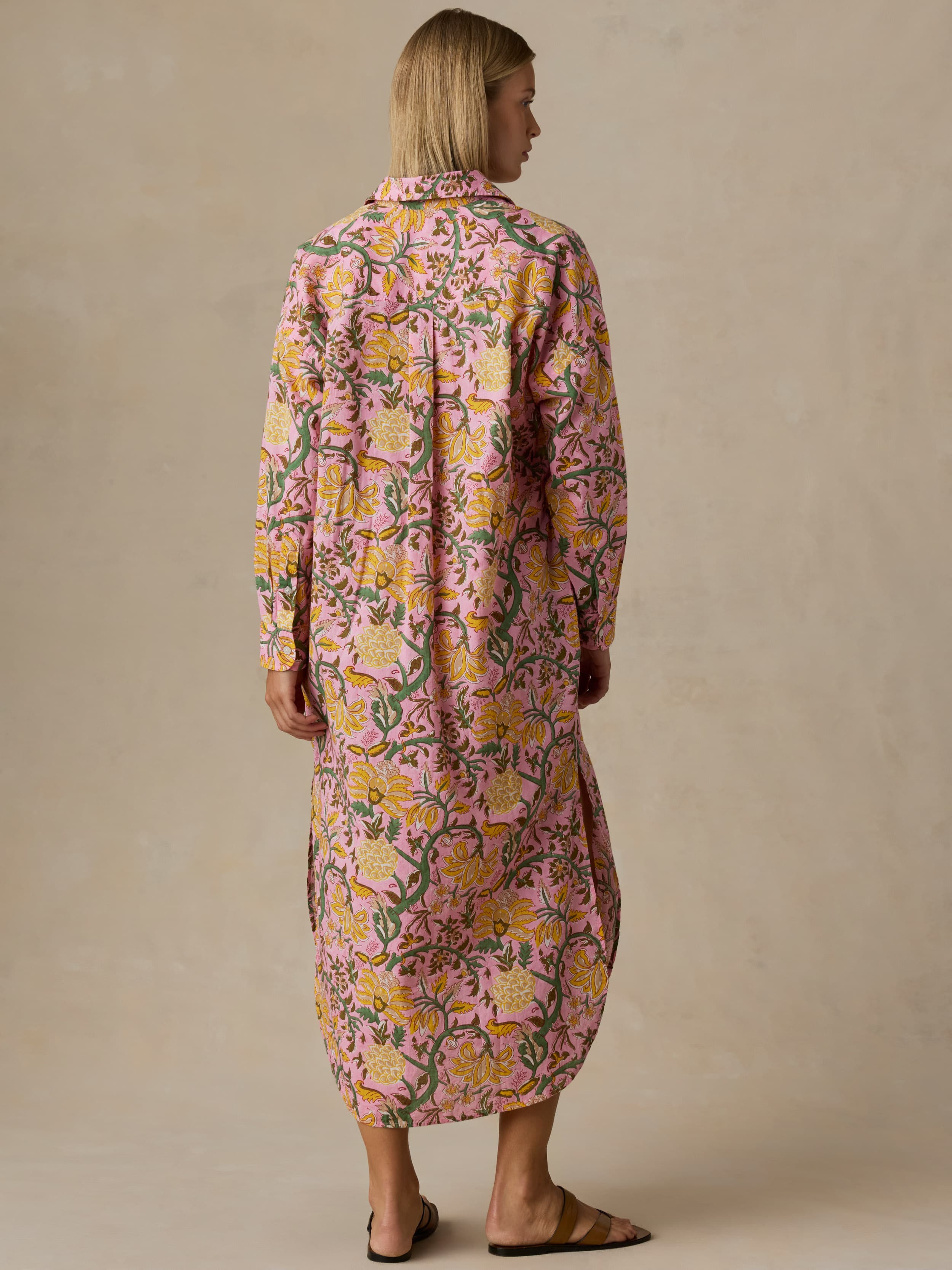 Woman wearing a long floral dress against a beige background