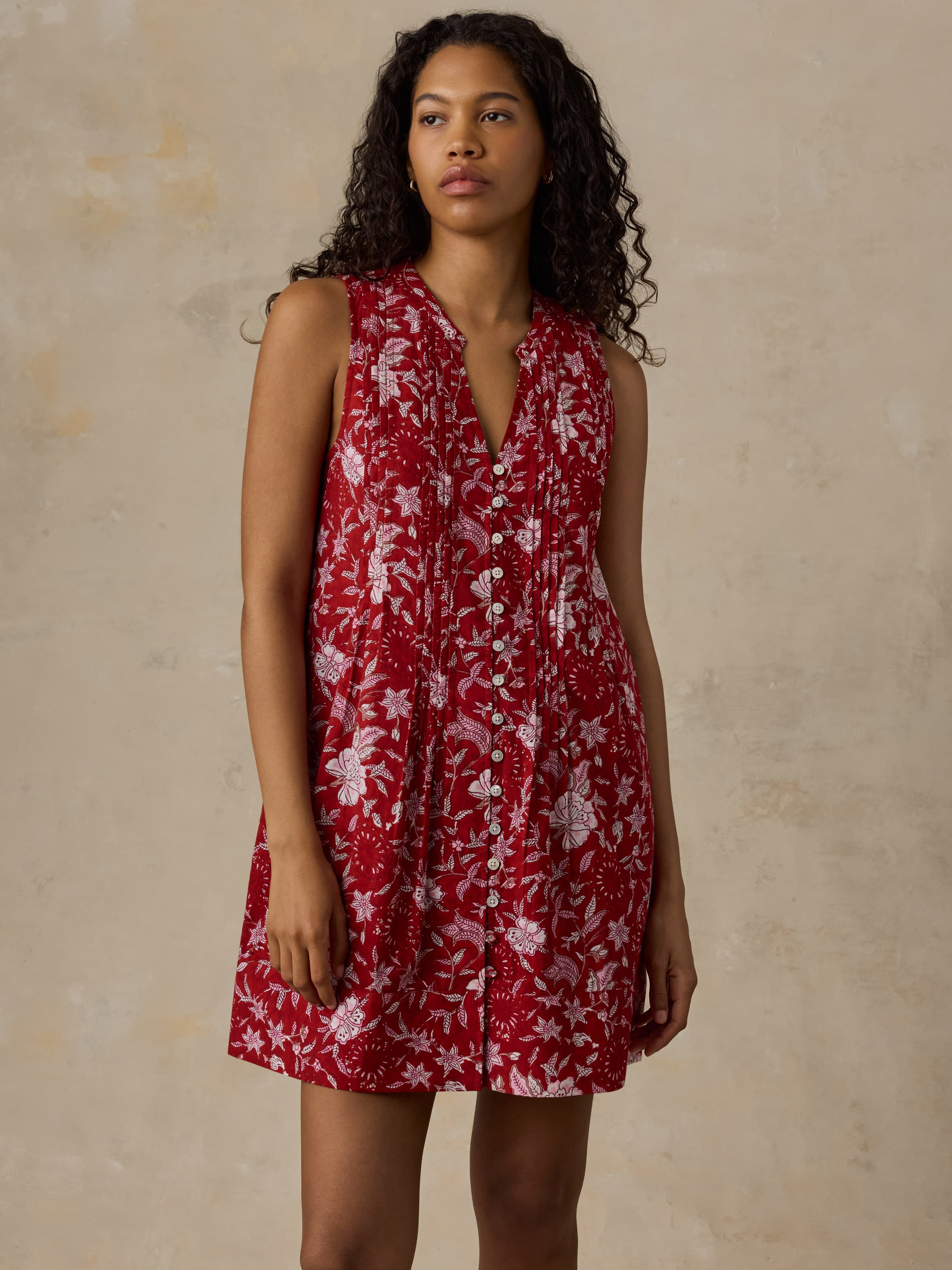 Woman wearing a red floral dress against a beige background
