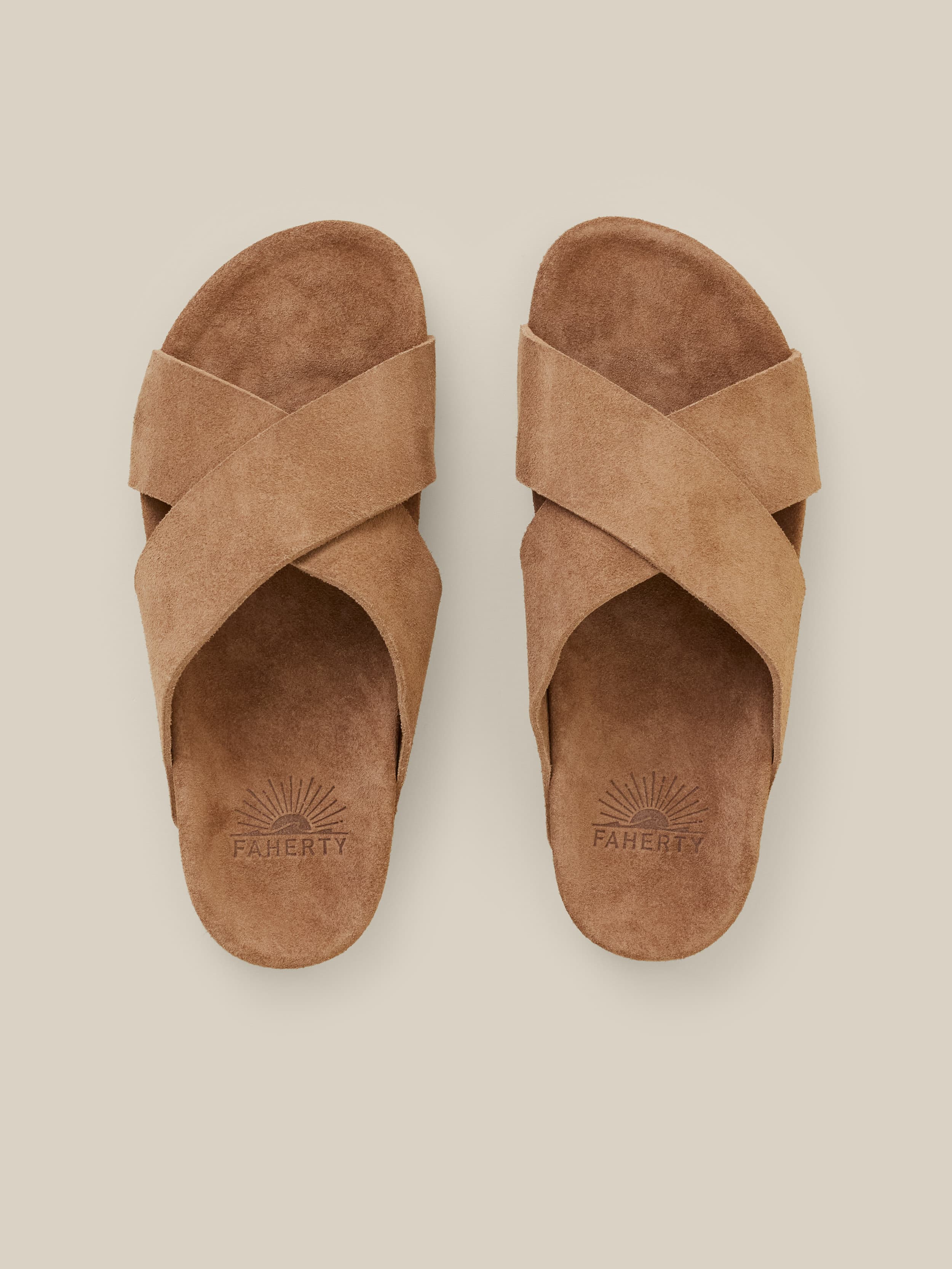 Brown suede sandals against a beige background