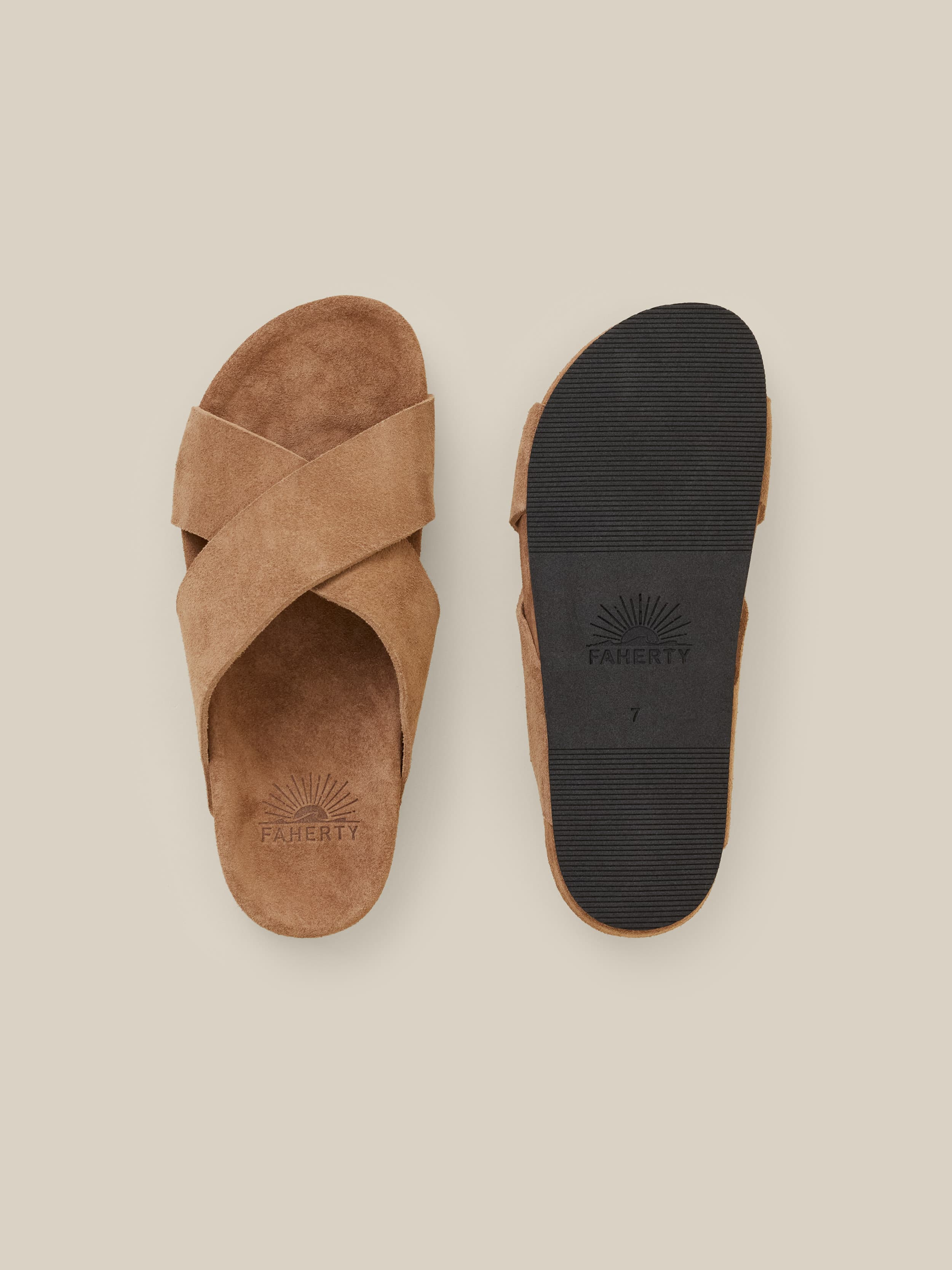Brown suede sandals against a beige background