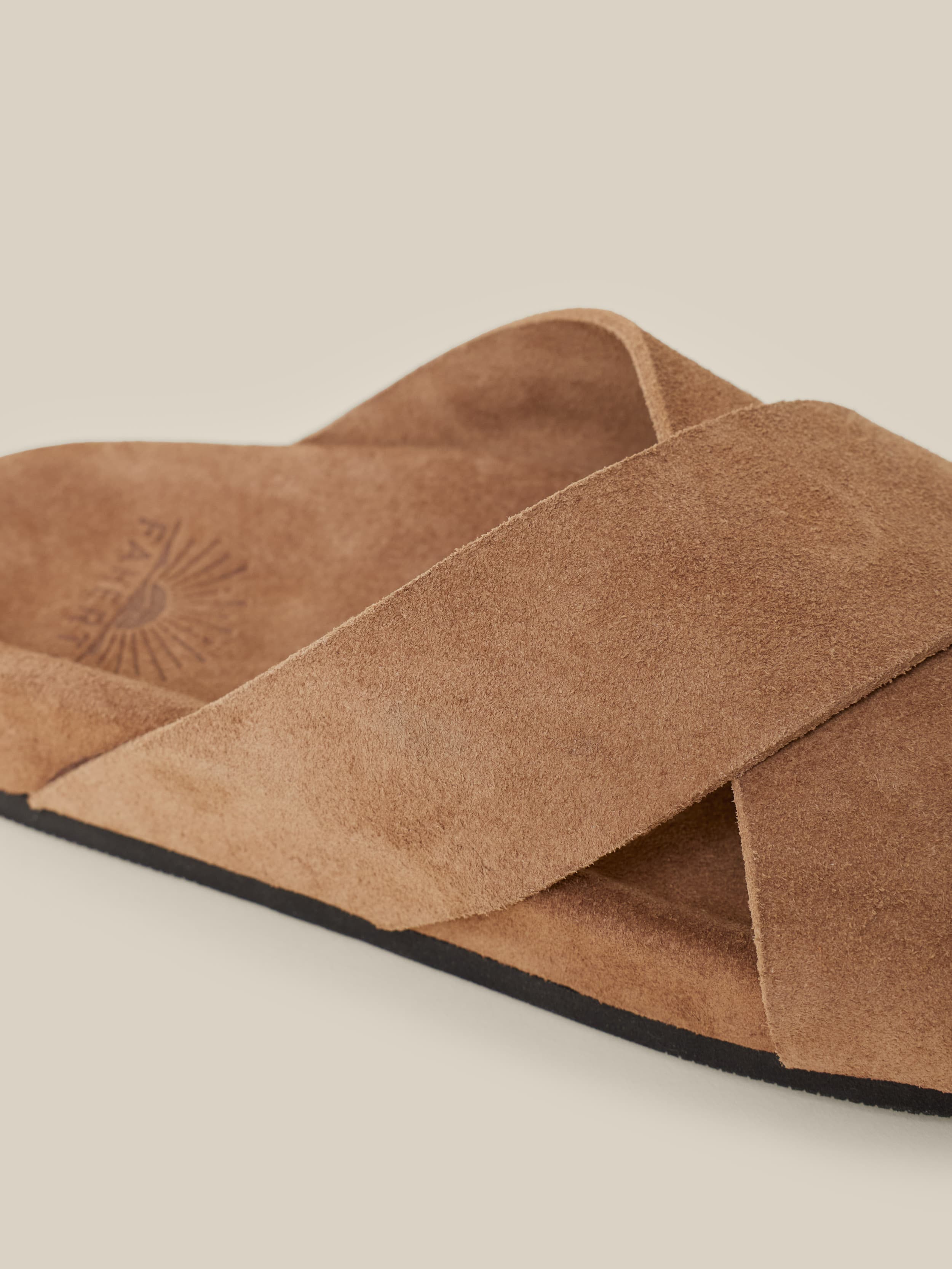 Brown suede sandals against a beige background