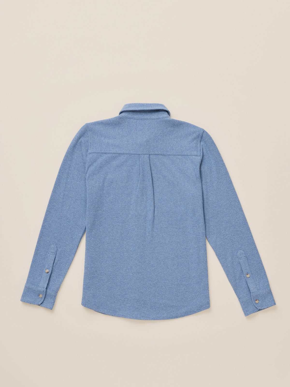 A light blue long-sleeve button-up shirt shown from the back, laid flat on a warm beige background., image 7 of 7