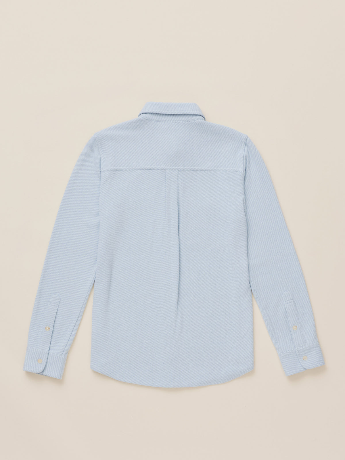 A light blue long-sleeve button-up shirt shown from the back, laid flat against a solid beige background., image 7 of 7