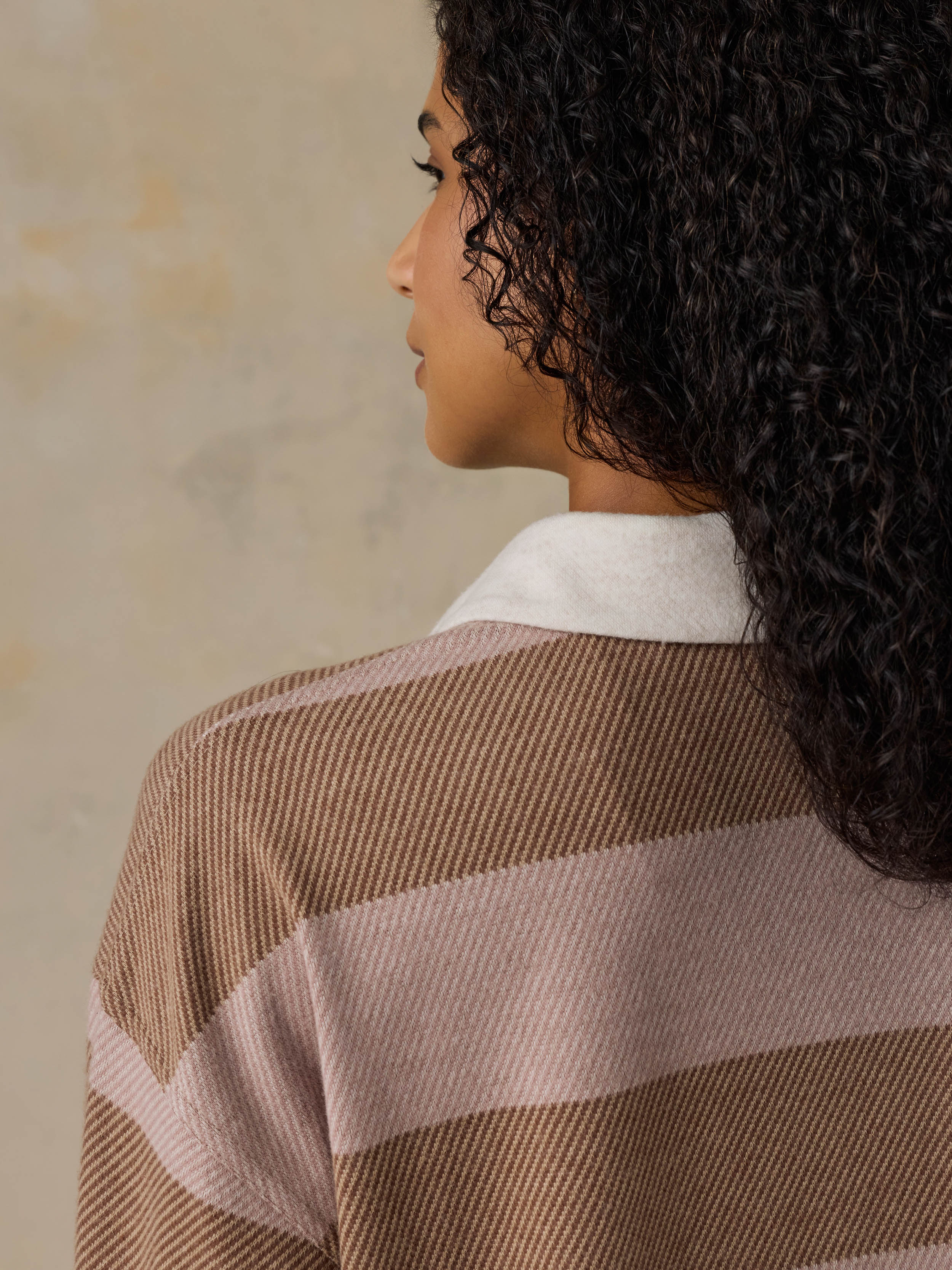 Woman wearing a brown and beige striped shirt against a beige background
