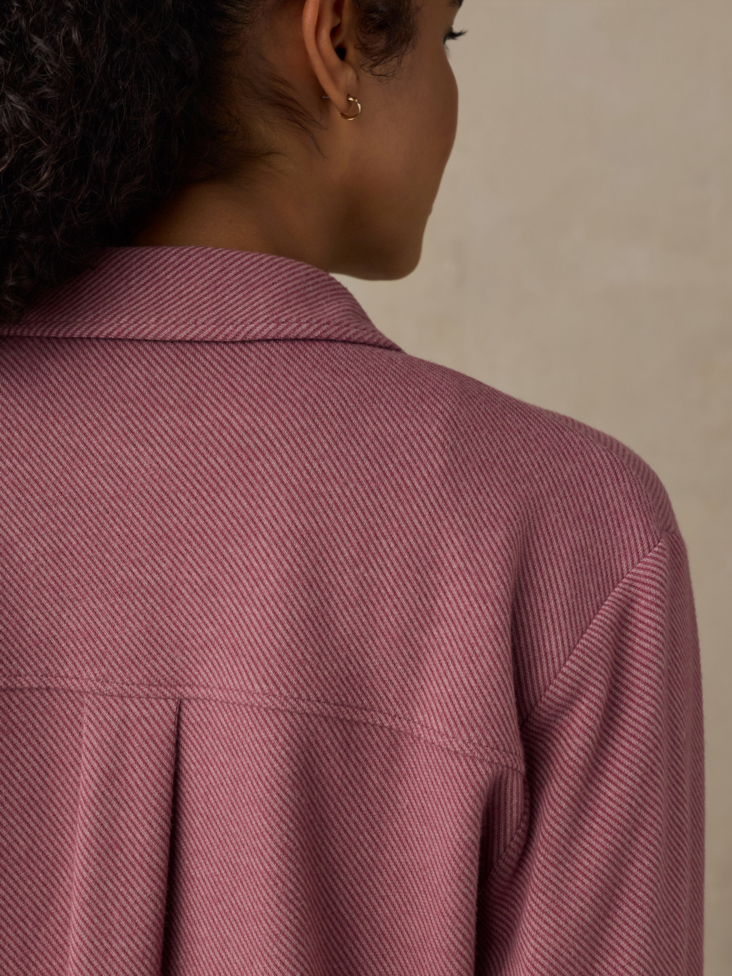 Woman wearing a pink button down shirt against a beige background