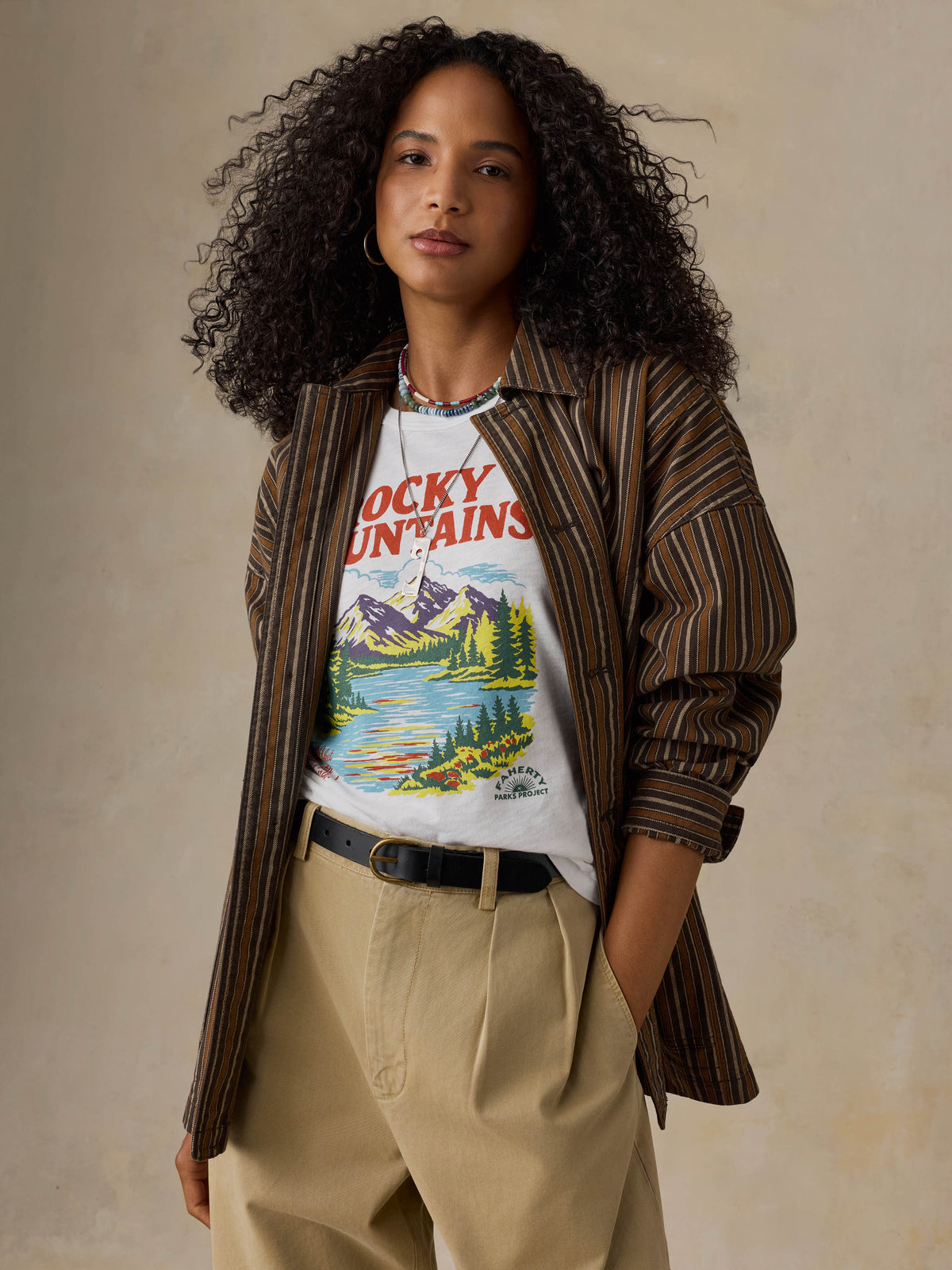 Woman wearing a white t-shirt with 'Rocky Mountains' design on a beige background, image 5 of 7