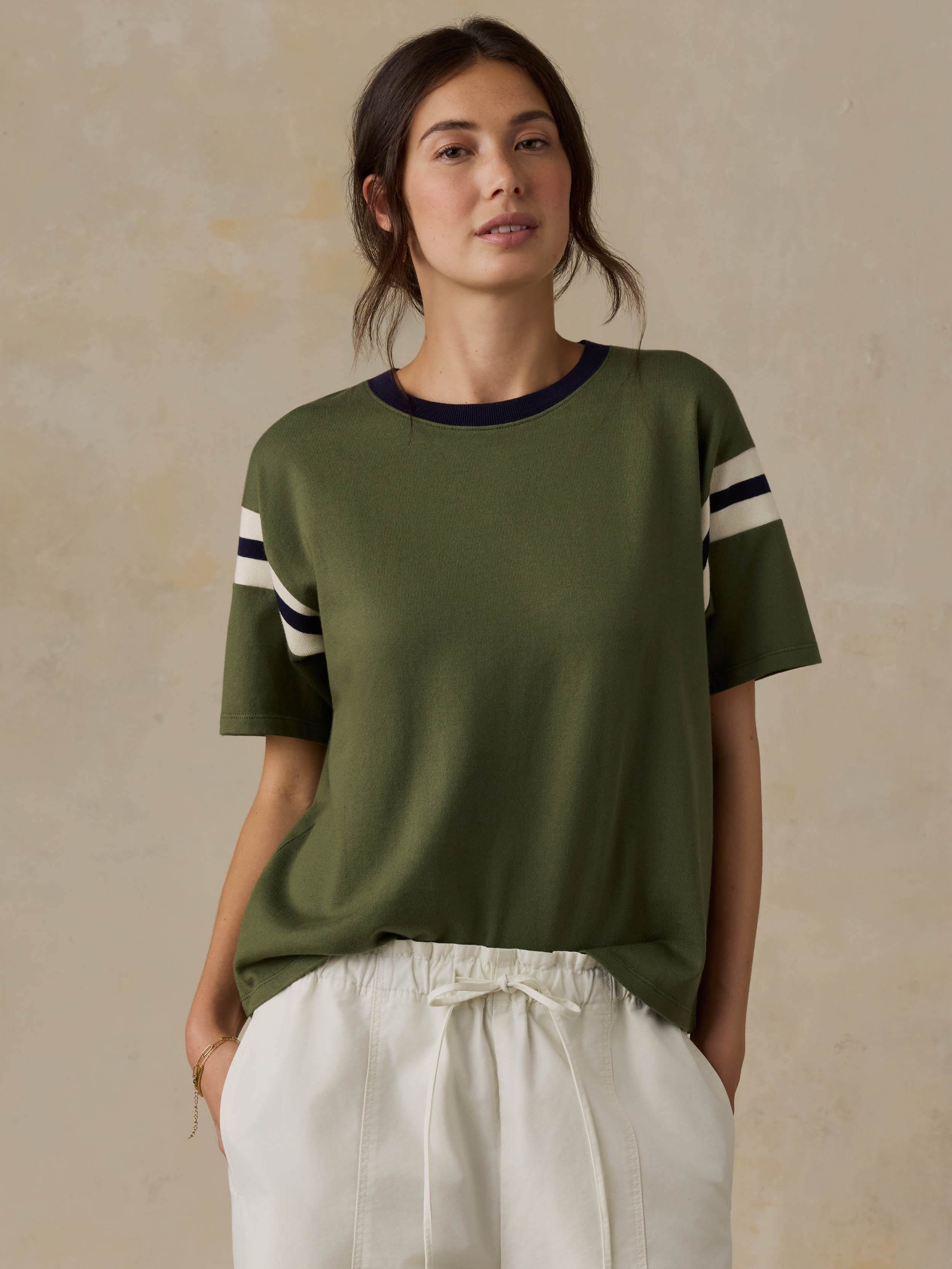 Woman wearing a green t-shirt with white stripes on a beige background