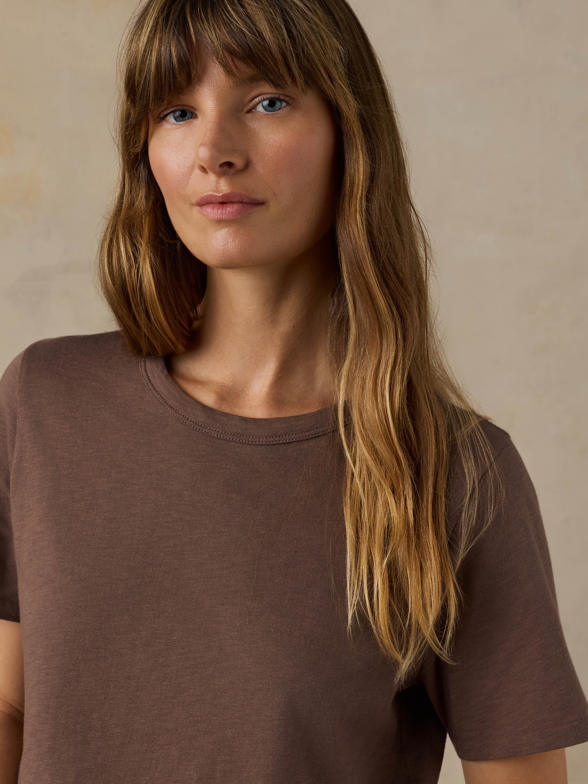 Woman wearing a brown t-shirt against a beige background