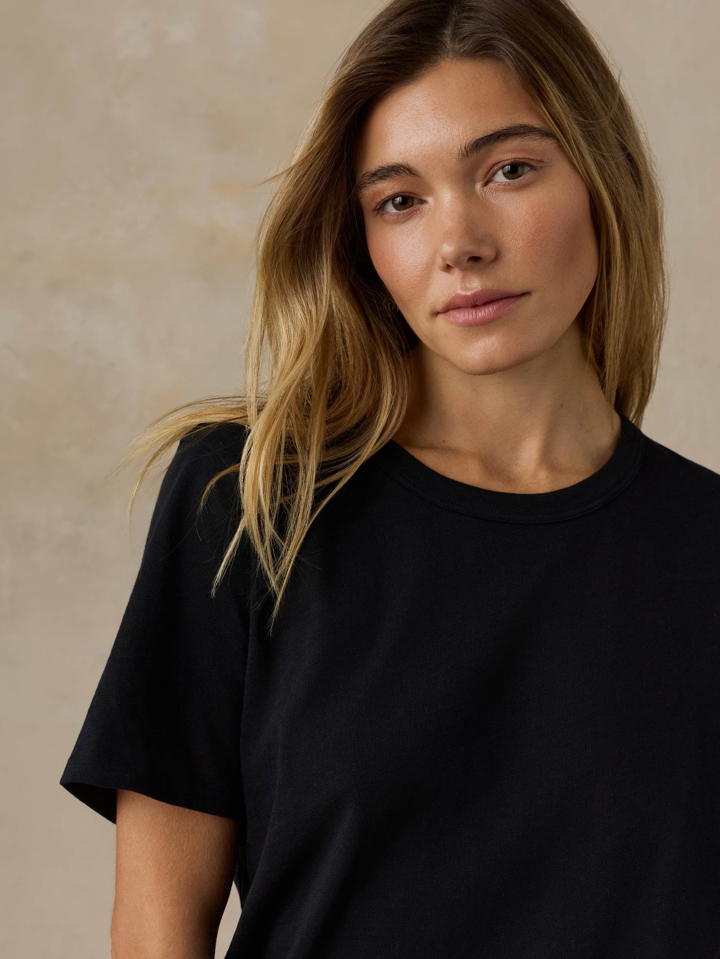 Woman wearing a black t-shirt against a beige background
