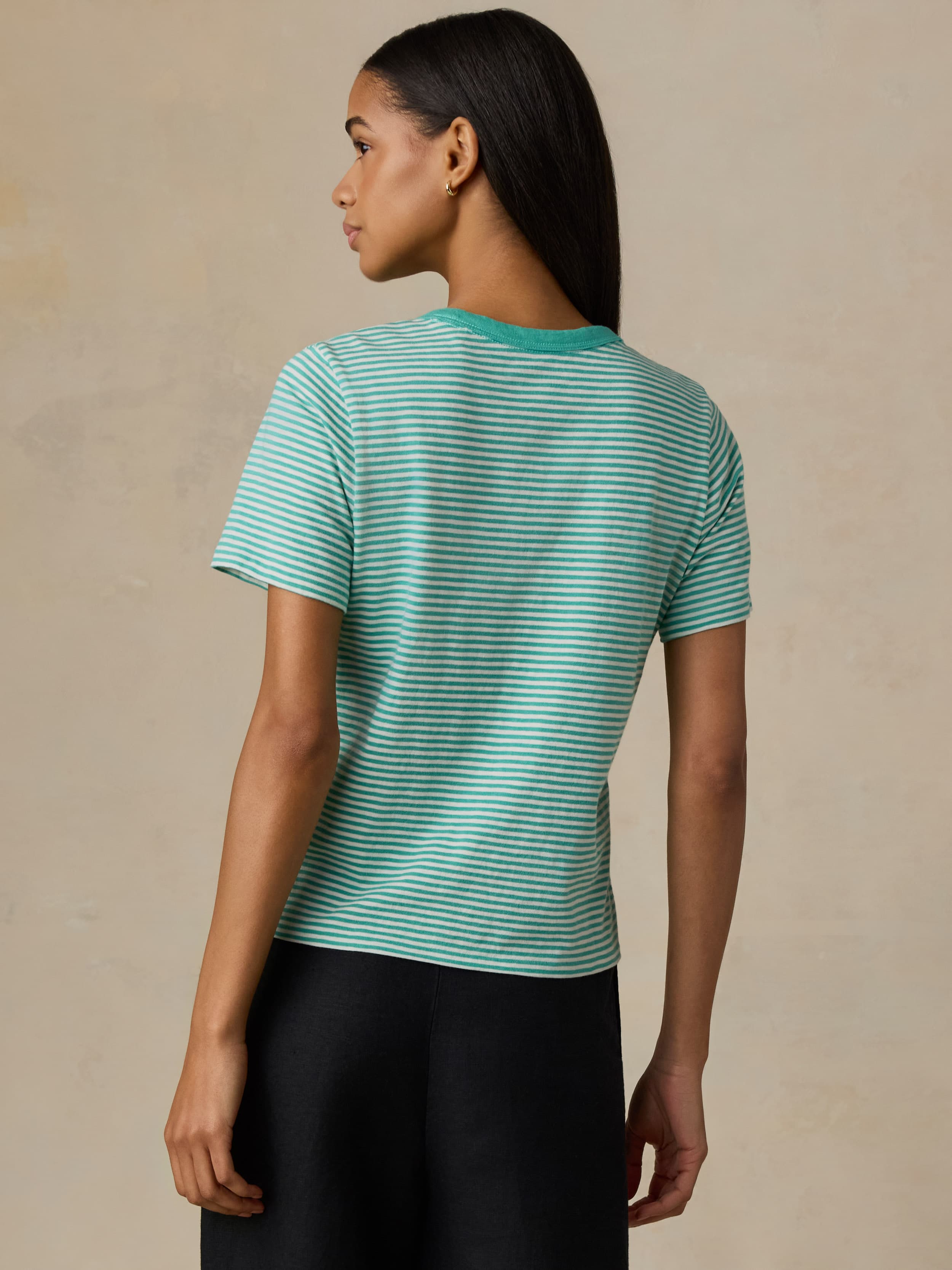 Woman wearing a green striped shirt against a beige background