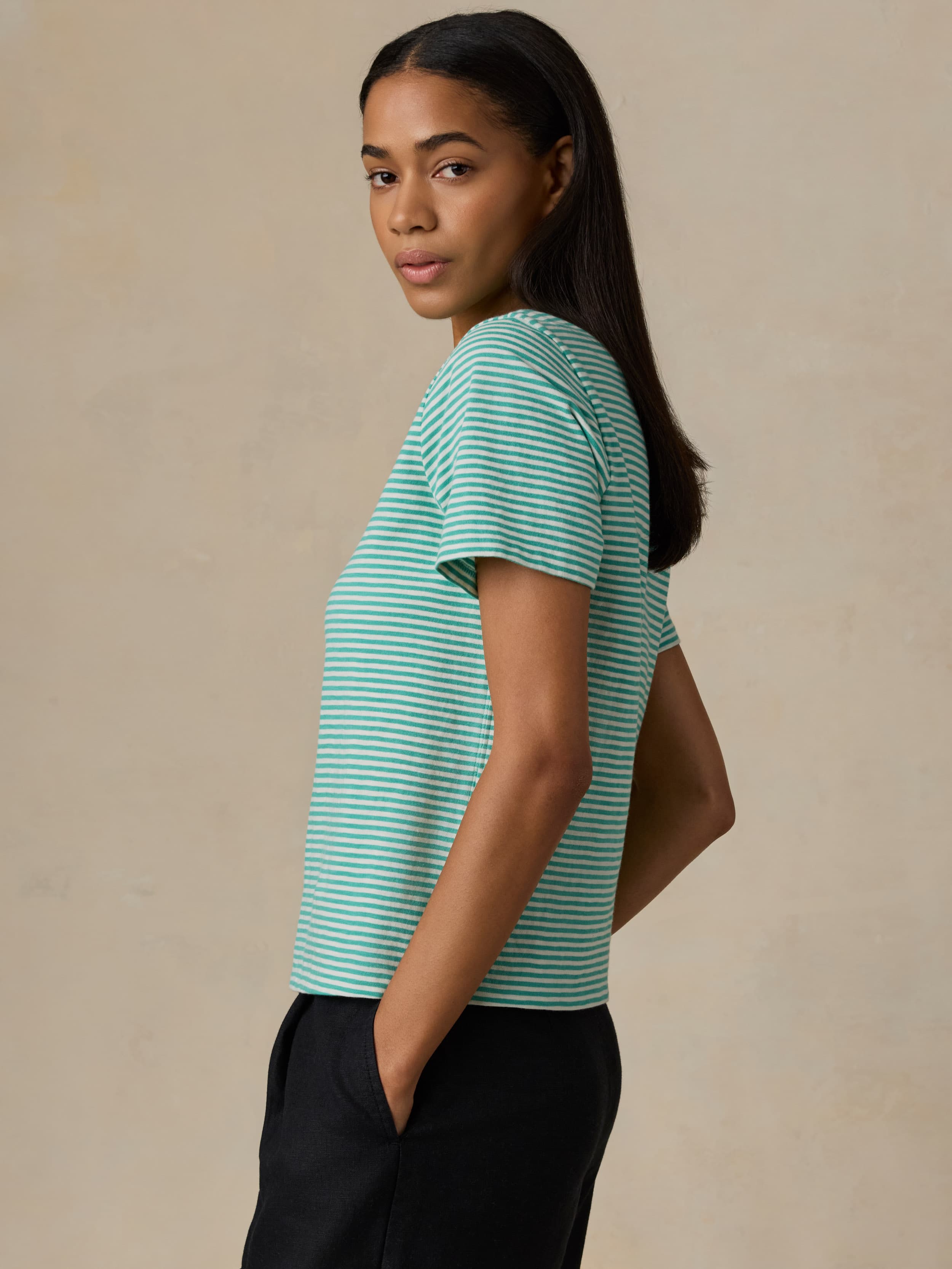 Woman wearing a green and white striped shirt against a beige background