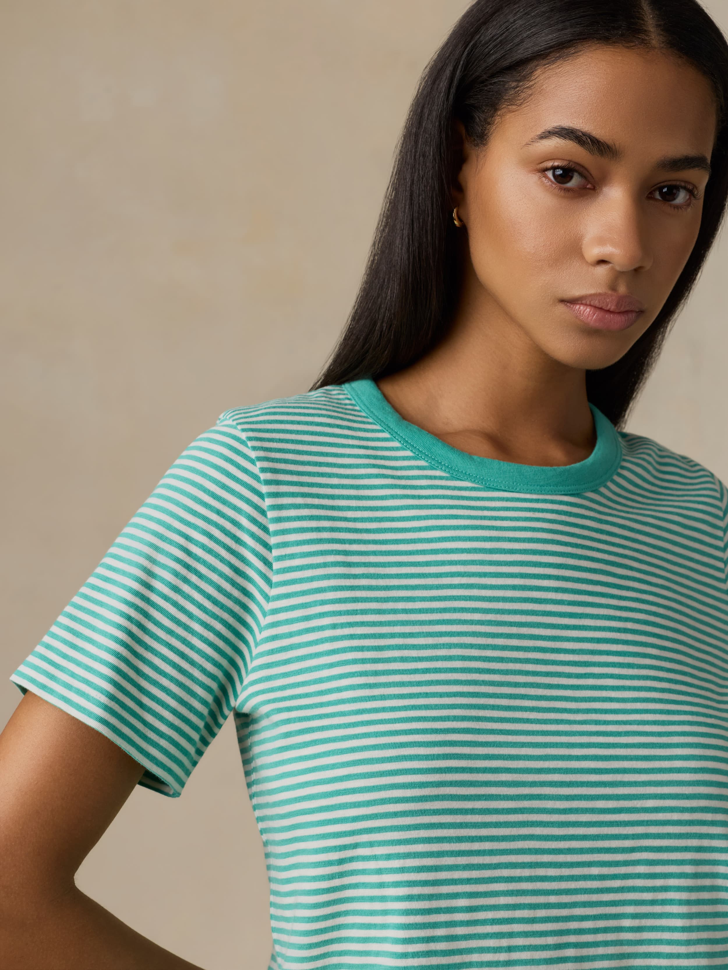 Woman wearing a green and white striped shirt against a beige background