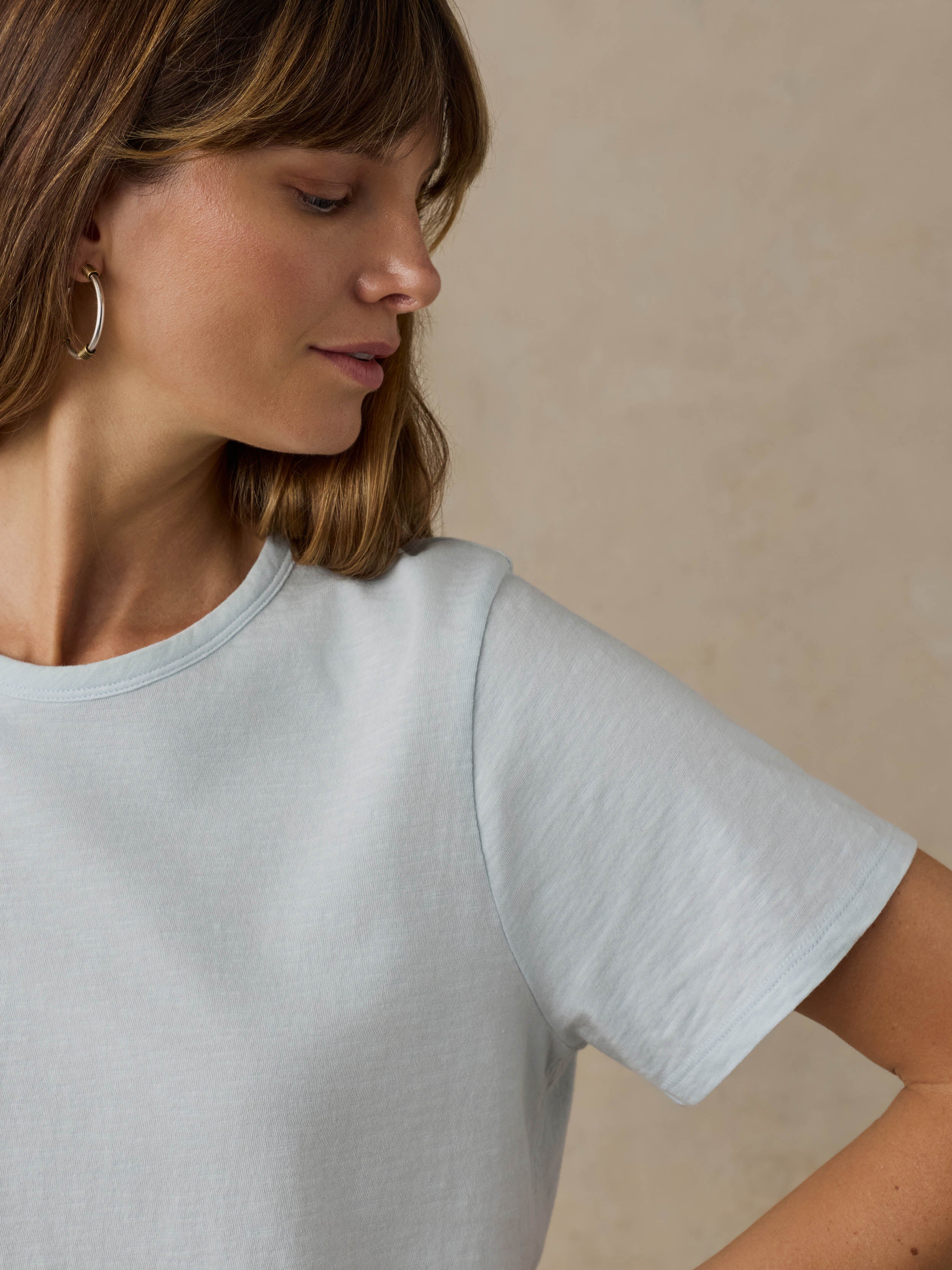 Woman wearing a light blue t-shirt against a beige background