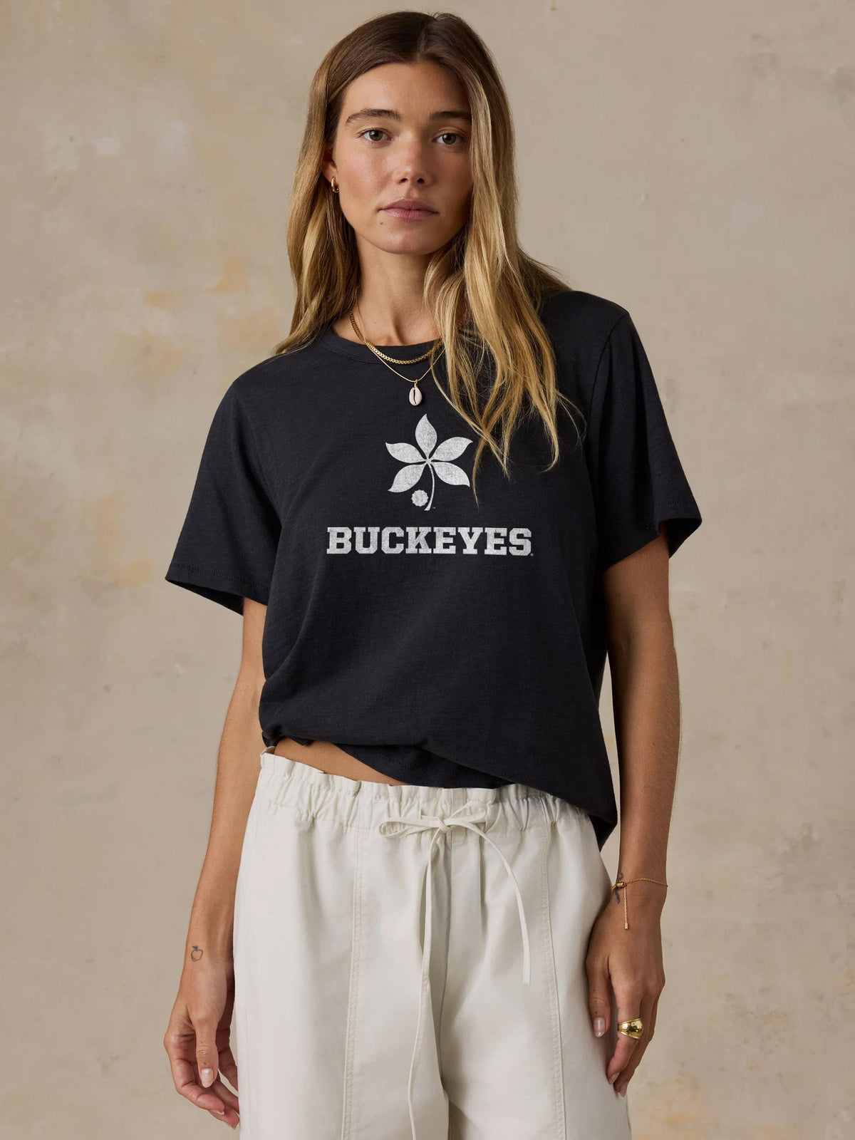 A woman wearing a black Ohio State tee and white pants, image 1 of 1