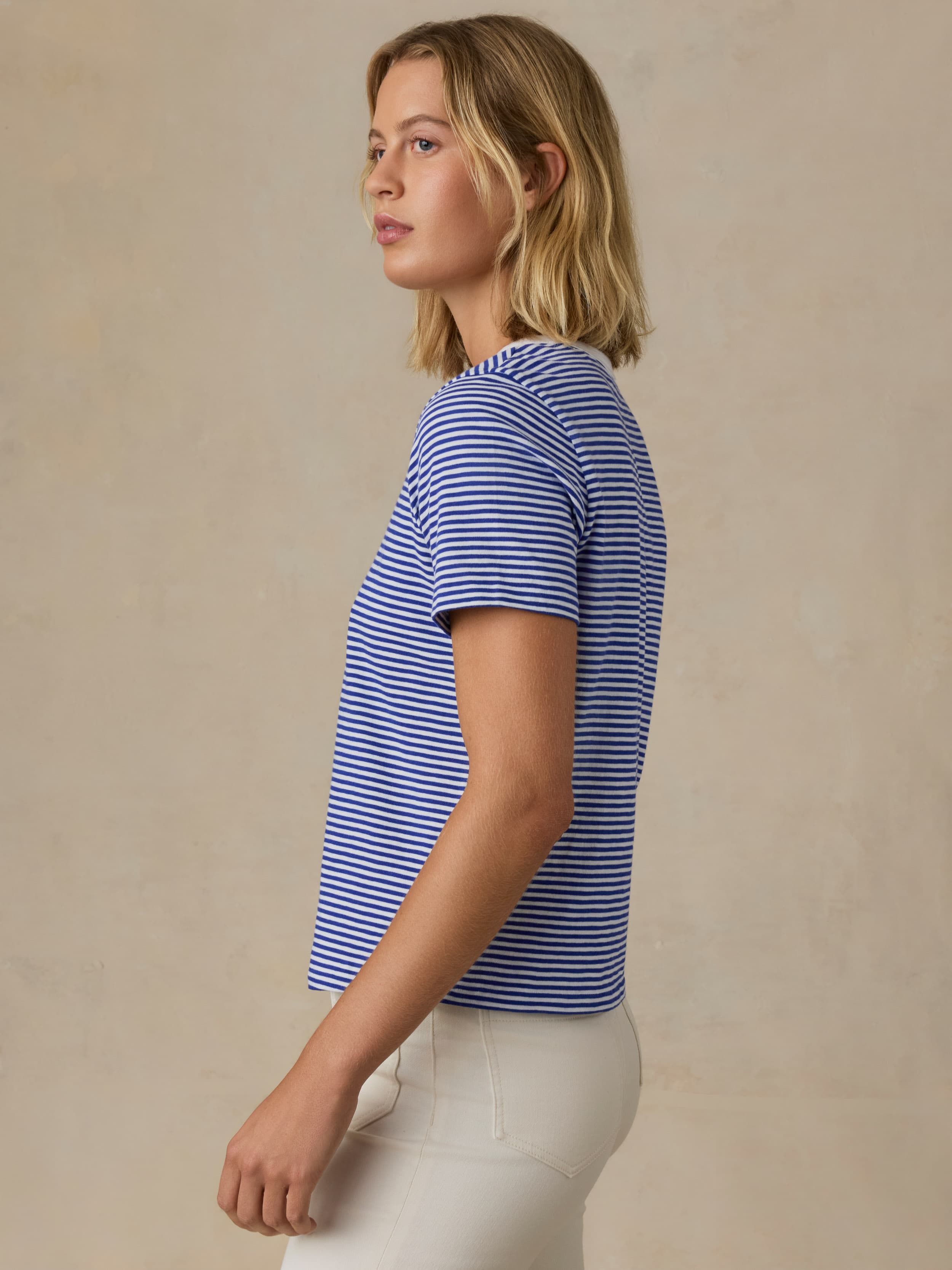 Woman wearing a blue and white striped shirt against a beige background