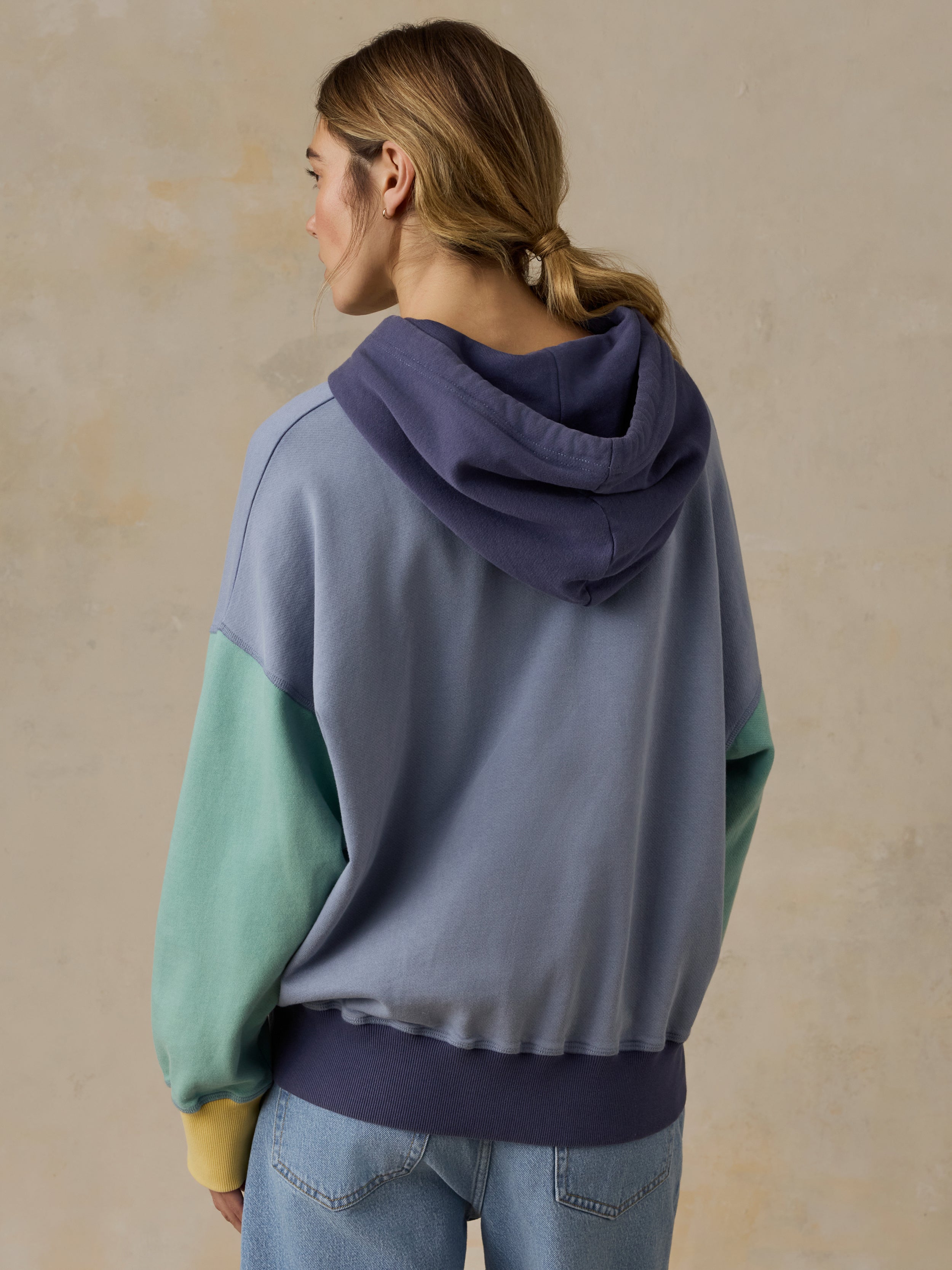 Woman wearing a colorful hoodie against a beige background