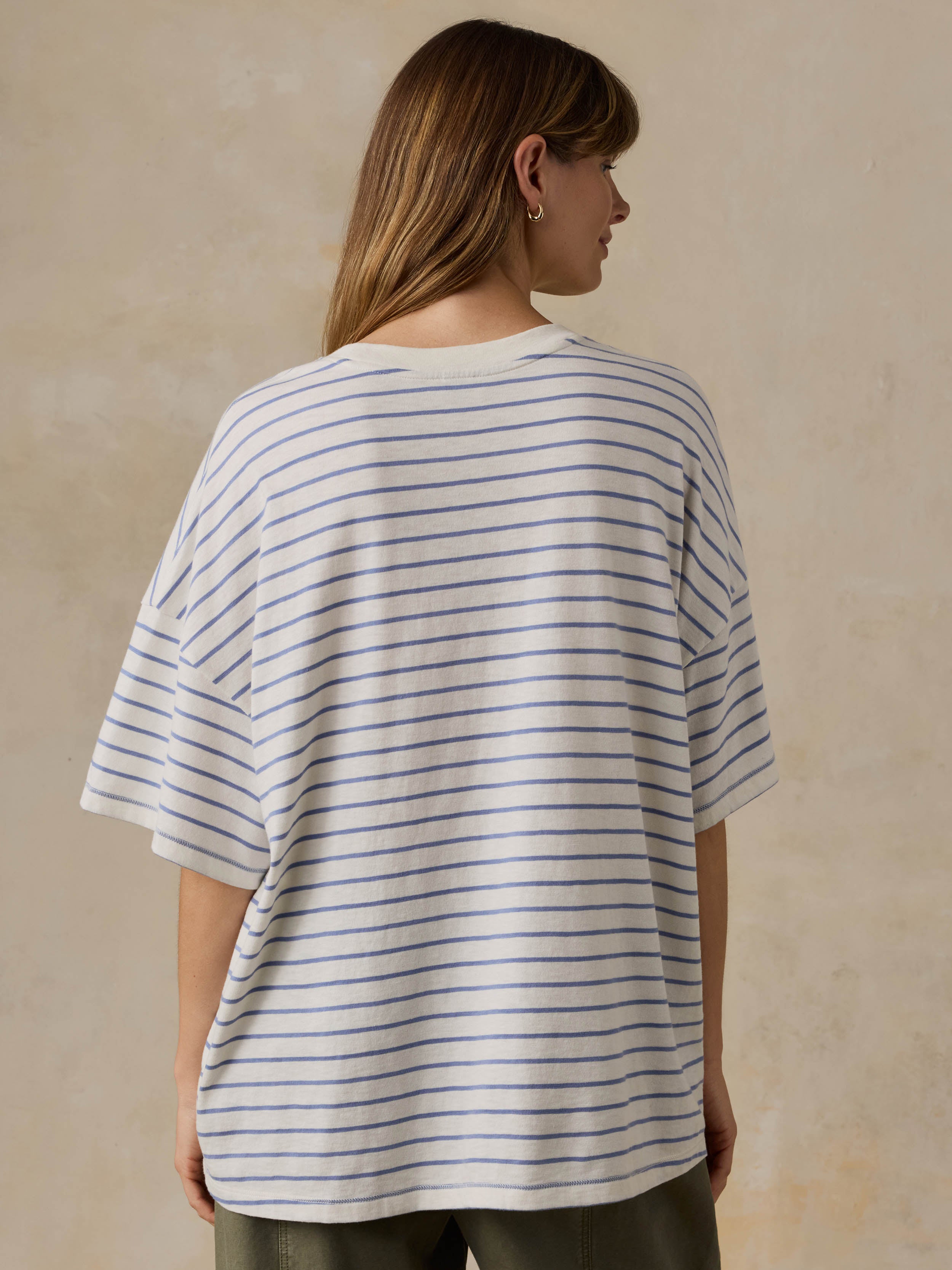 Woman wearing blue and white striped t-shirt and green pants against a beige background