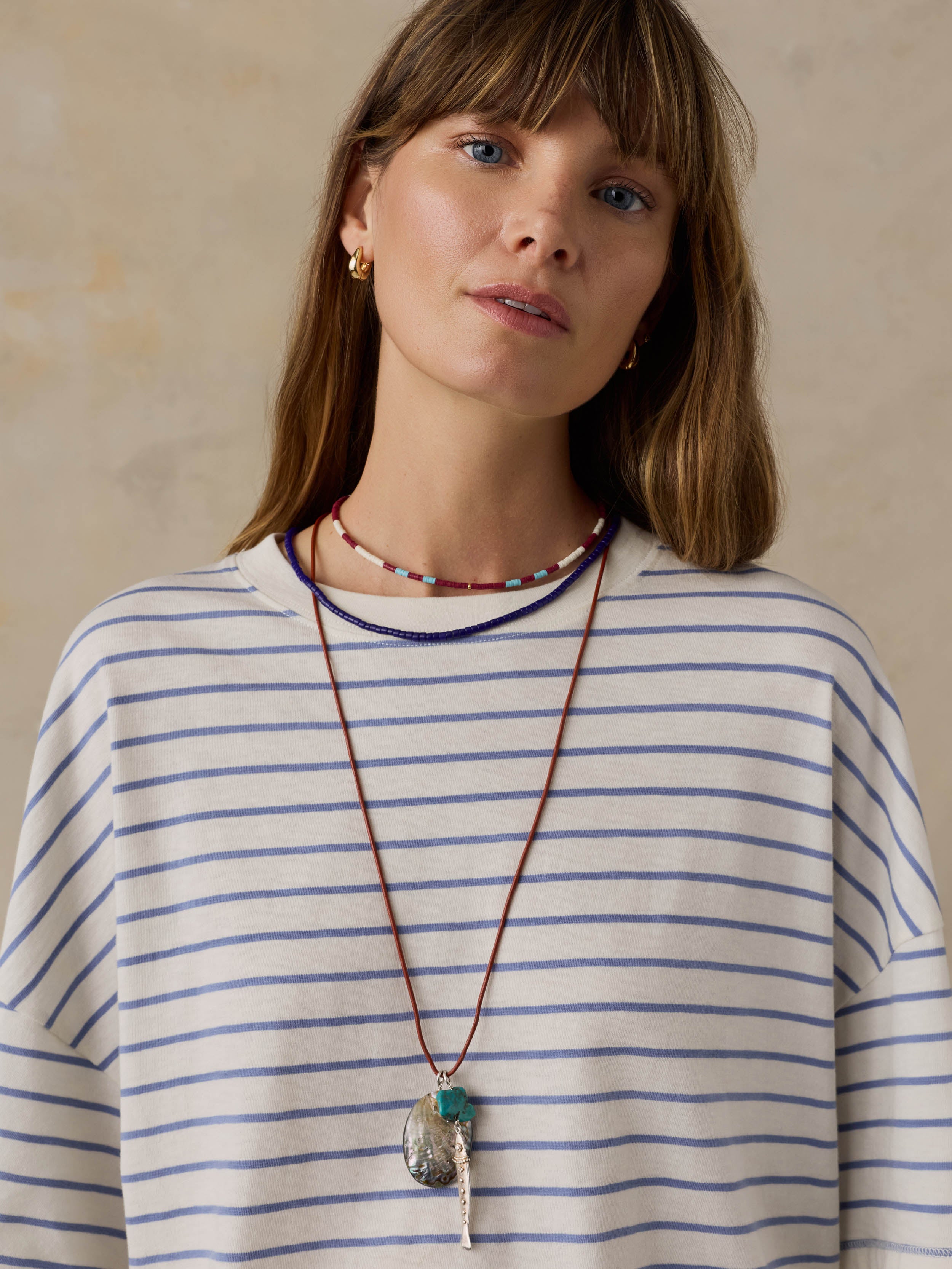 Woman wearing blue and white striped t-shirt against a beige background