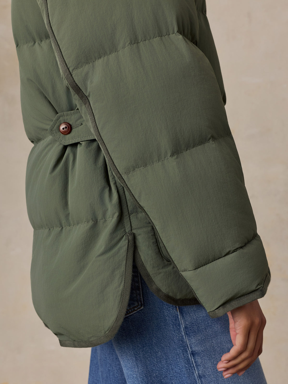 Close up of a woman wearing a green jacket and blue jeans, image 7 of 8