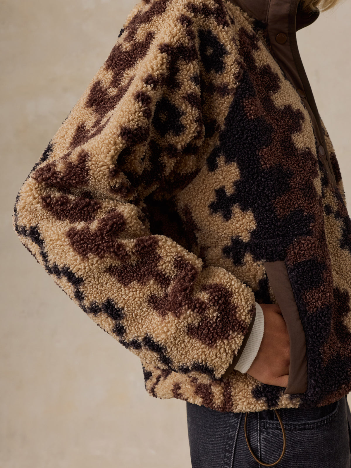 Close up of a woman wearing a brown printed fleece jacket and black jeans, image 4 of 5