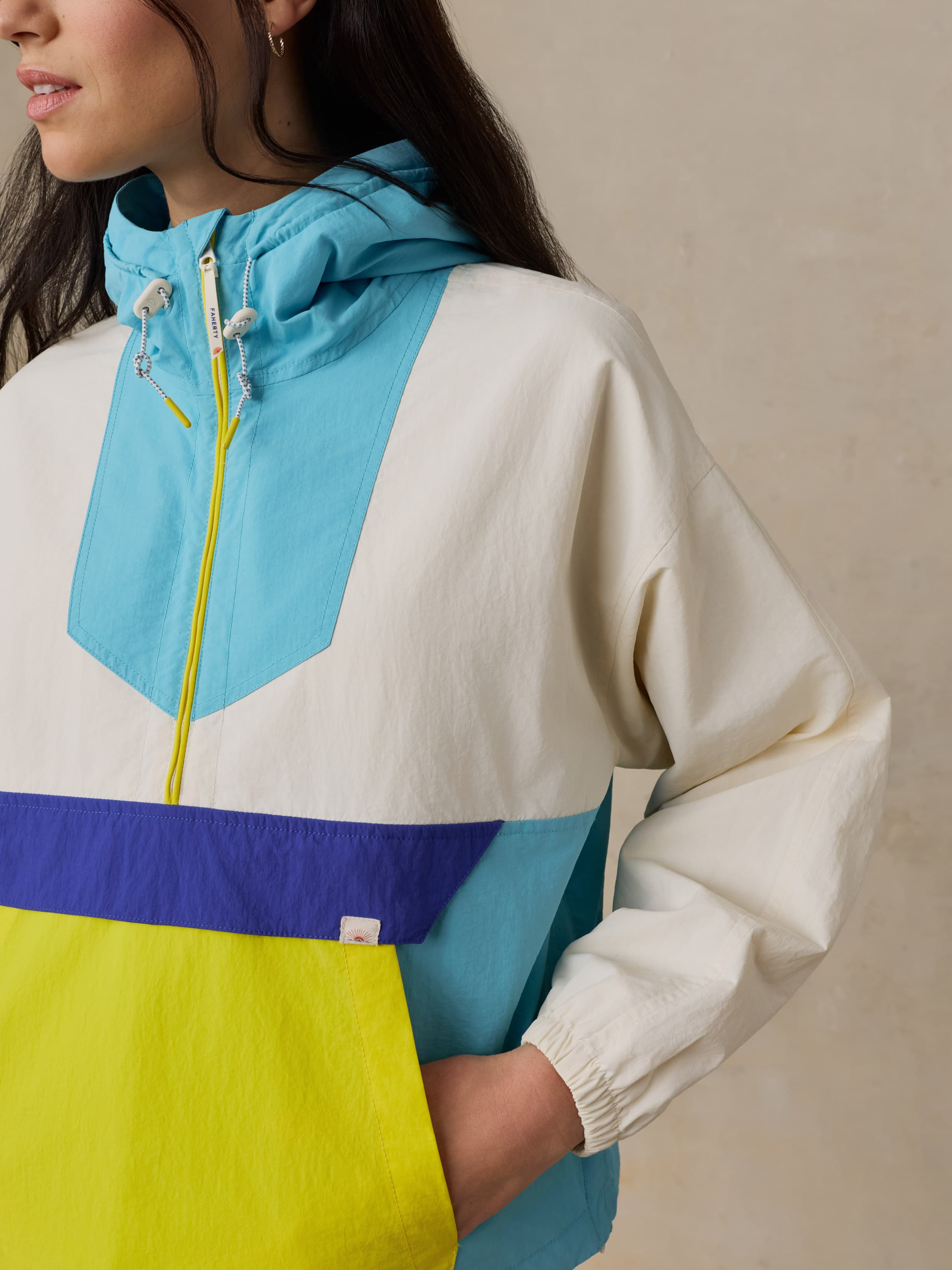 Woman wearing a colorful windbreaker jacket against a beige background