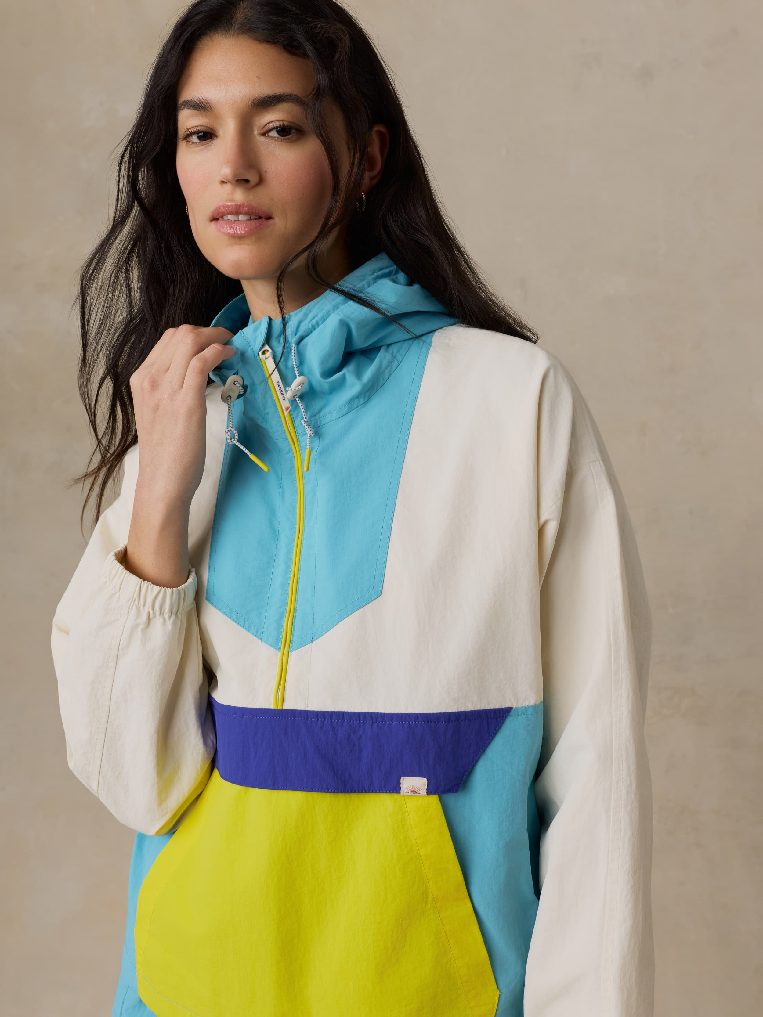 Woman wearing a colorful windbreaker jacket against a beige background
