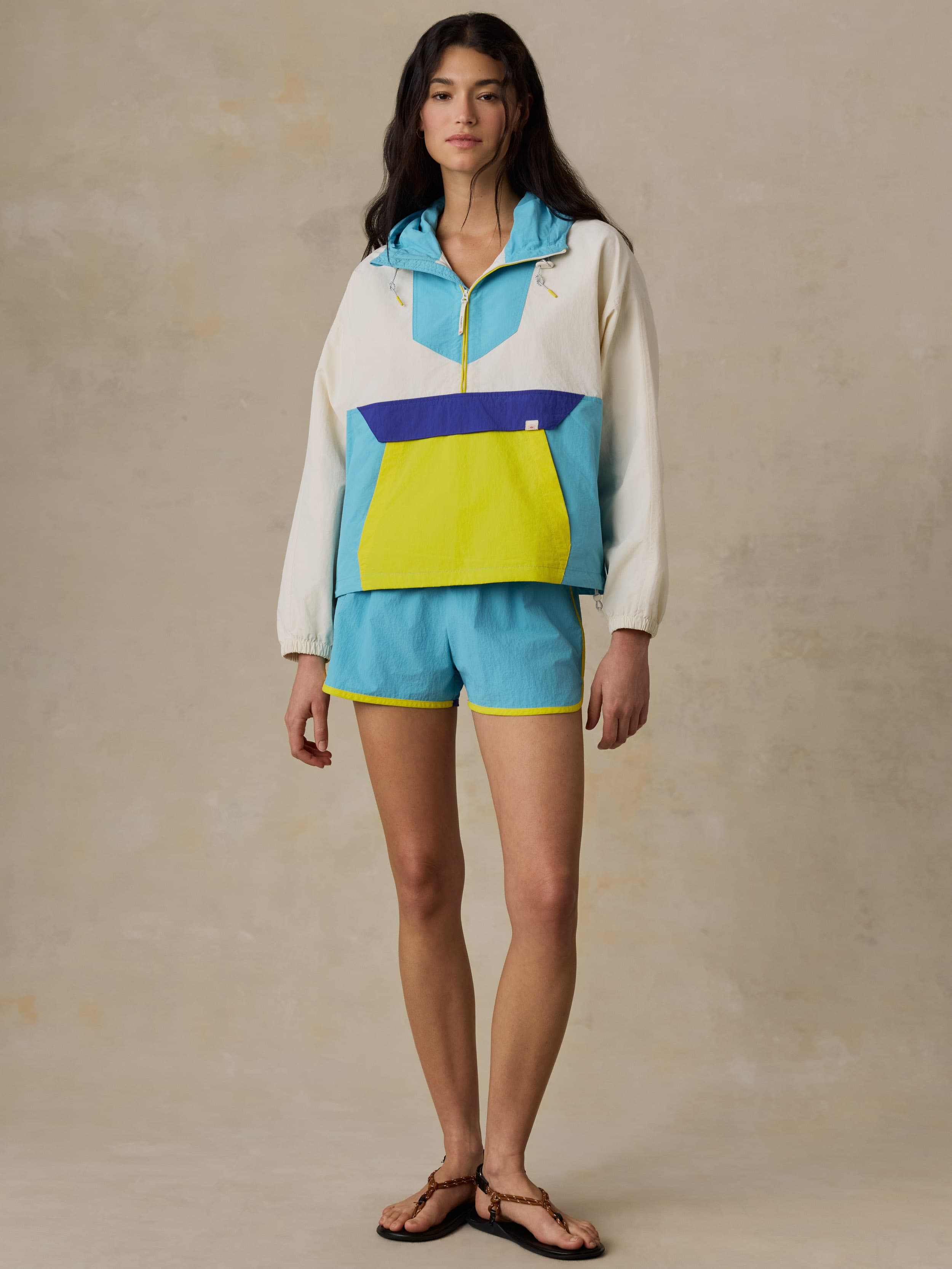 Woman wearing a colorful windbreaker jacket against a beige background