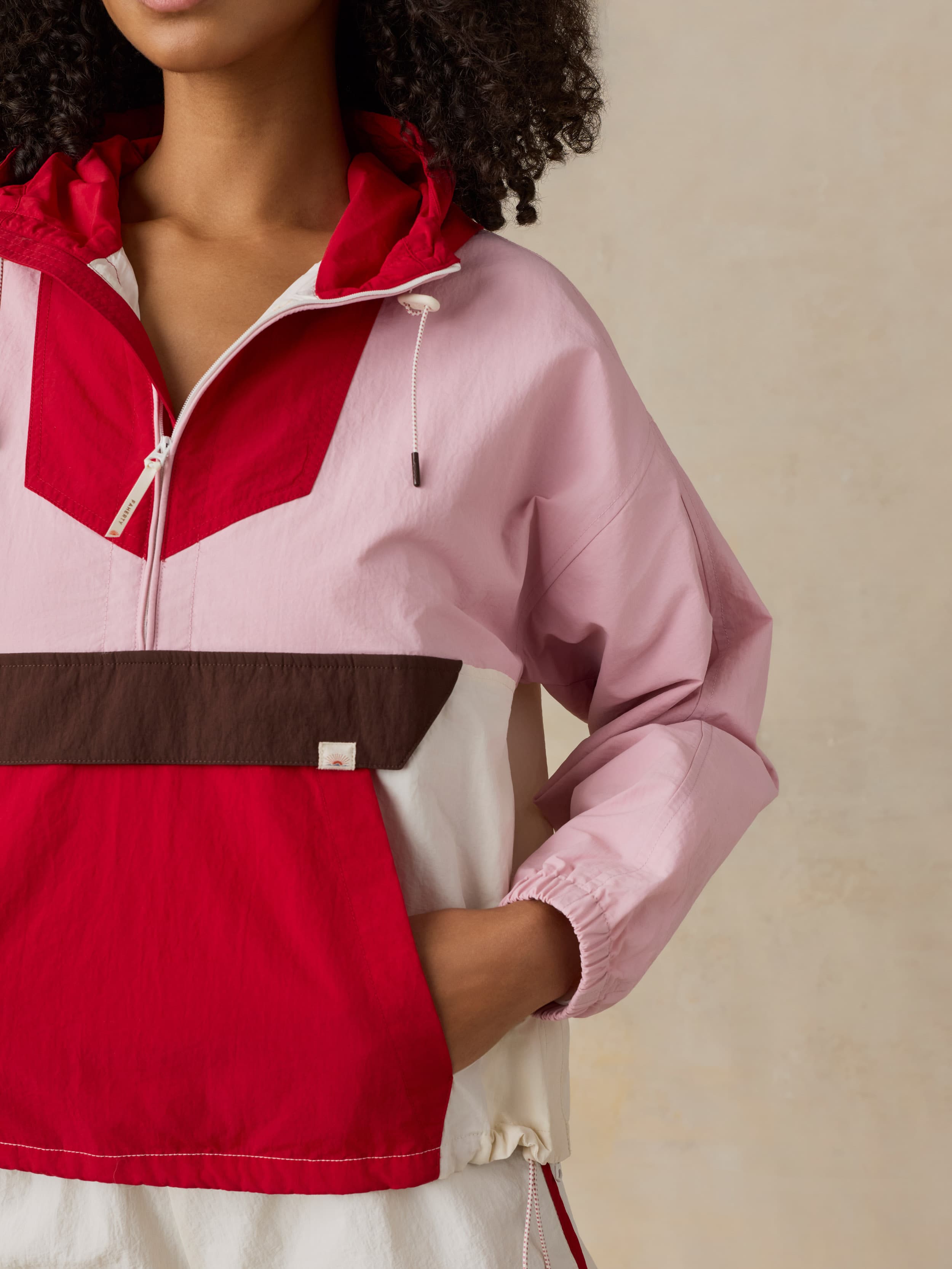 Woman wearing a colorful jacket with a red, pink, and brown design on a beige background