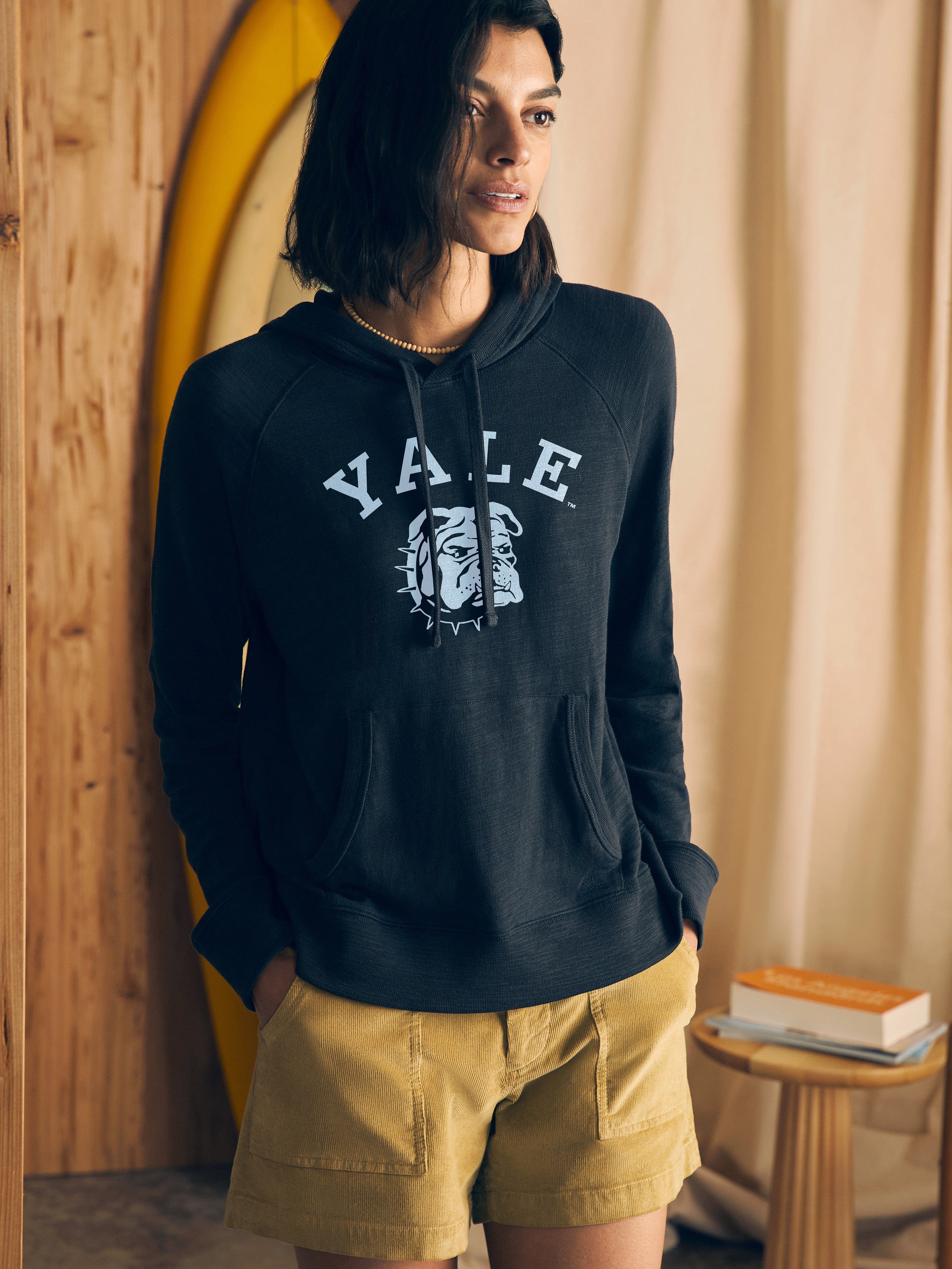 Woman wearing a black hoodie with Yale graphic at the center front in a casual setting
