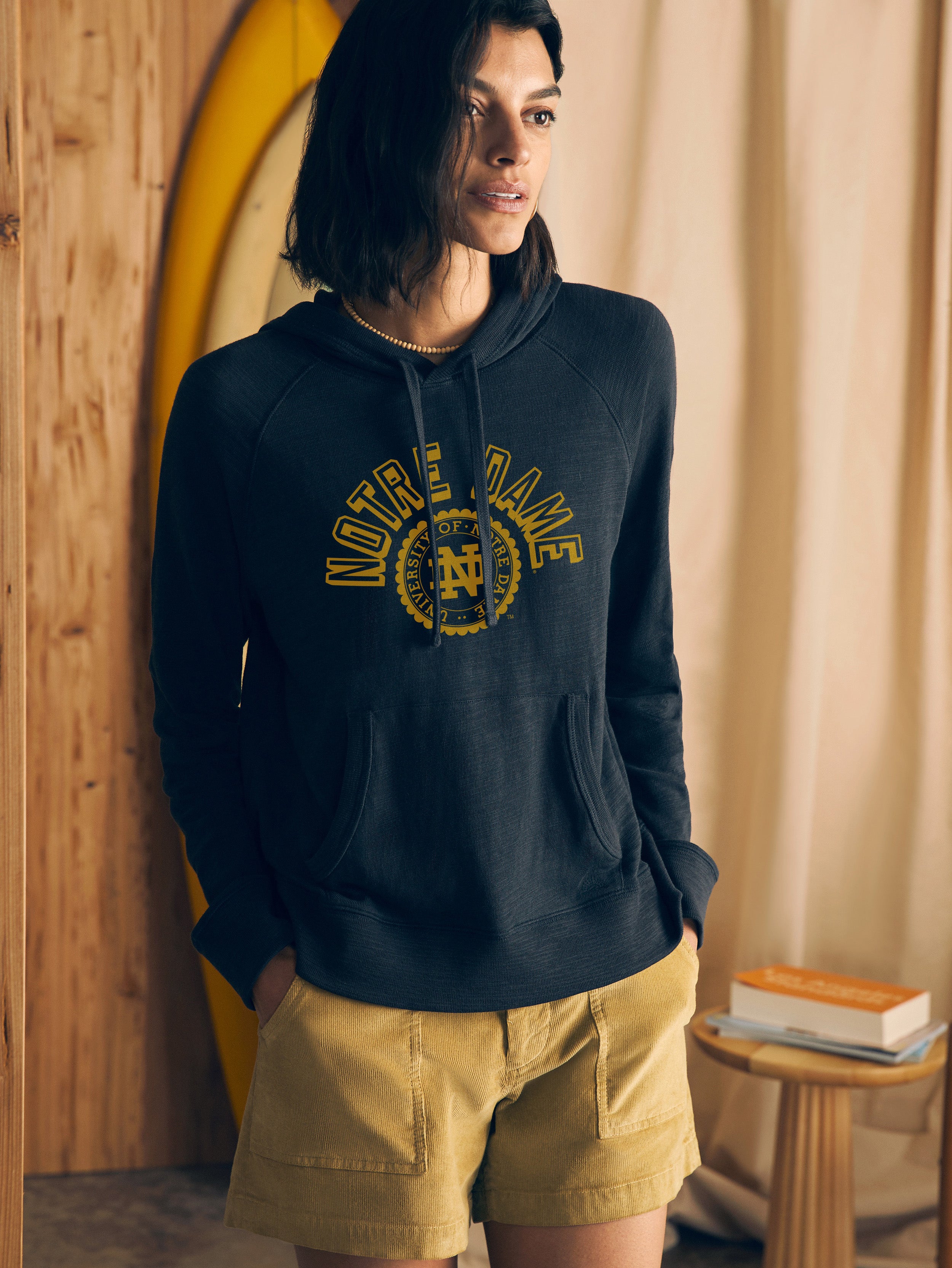 Woman wearing a navy hoodie with Notre Dame graphic on the center front against