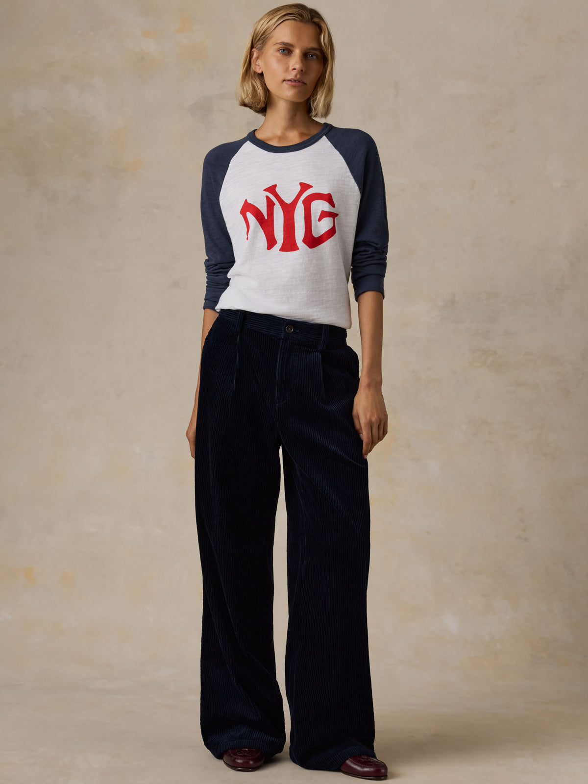 A woman wearing a white and blue NY Giants baseball tee with navy pants, image 1 of 5