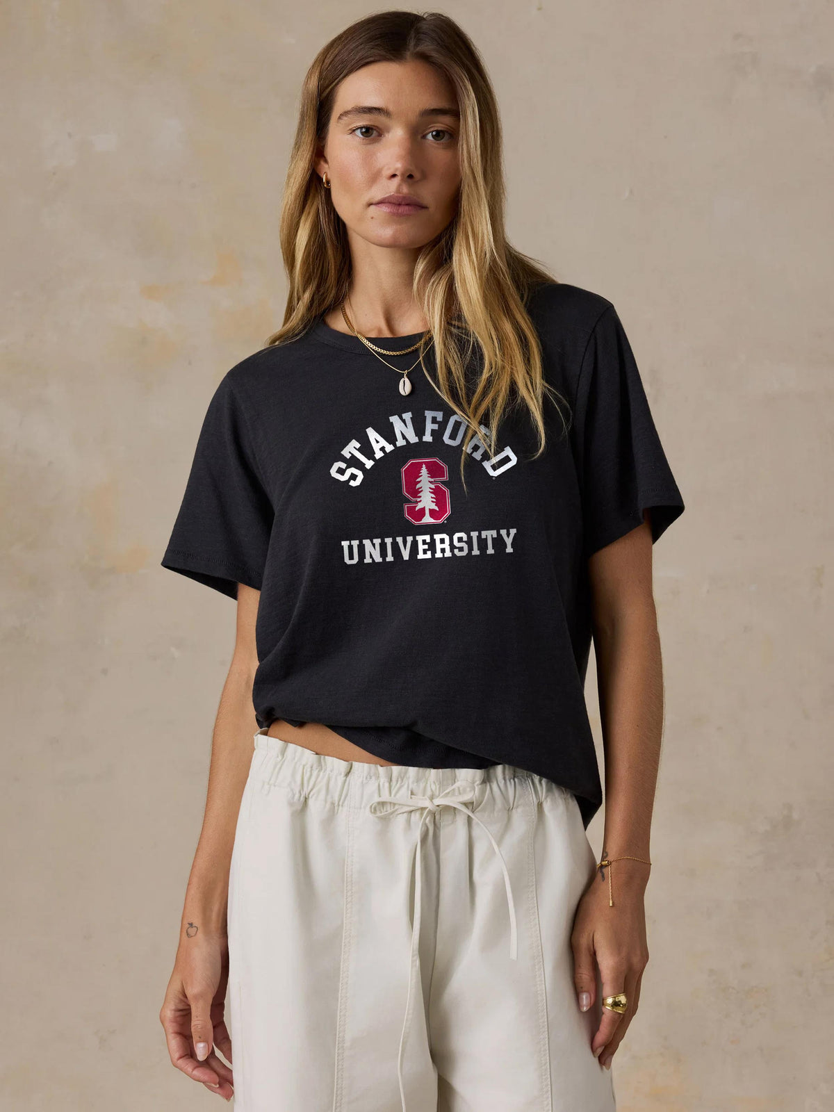 A woman wearing a black Stanford tee and white pants, image 1 of 1