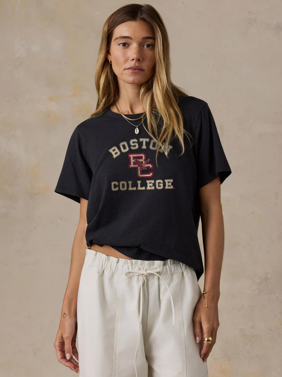 A woman wearing a black Boston College tee and white pants, image 1 of 1