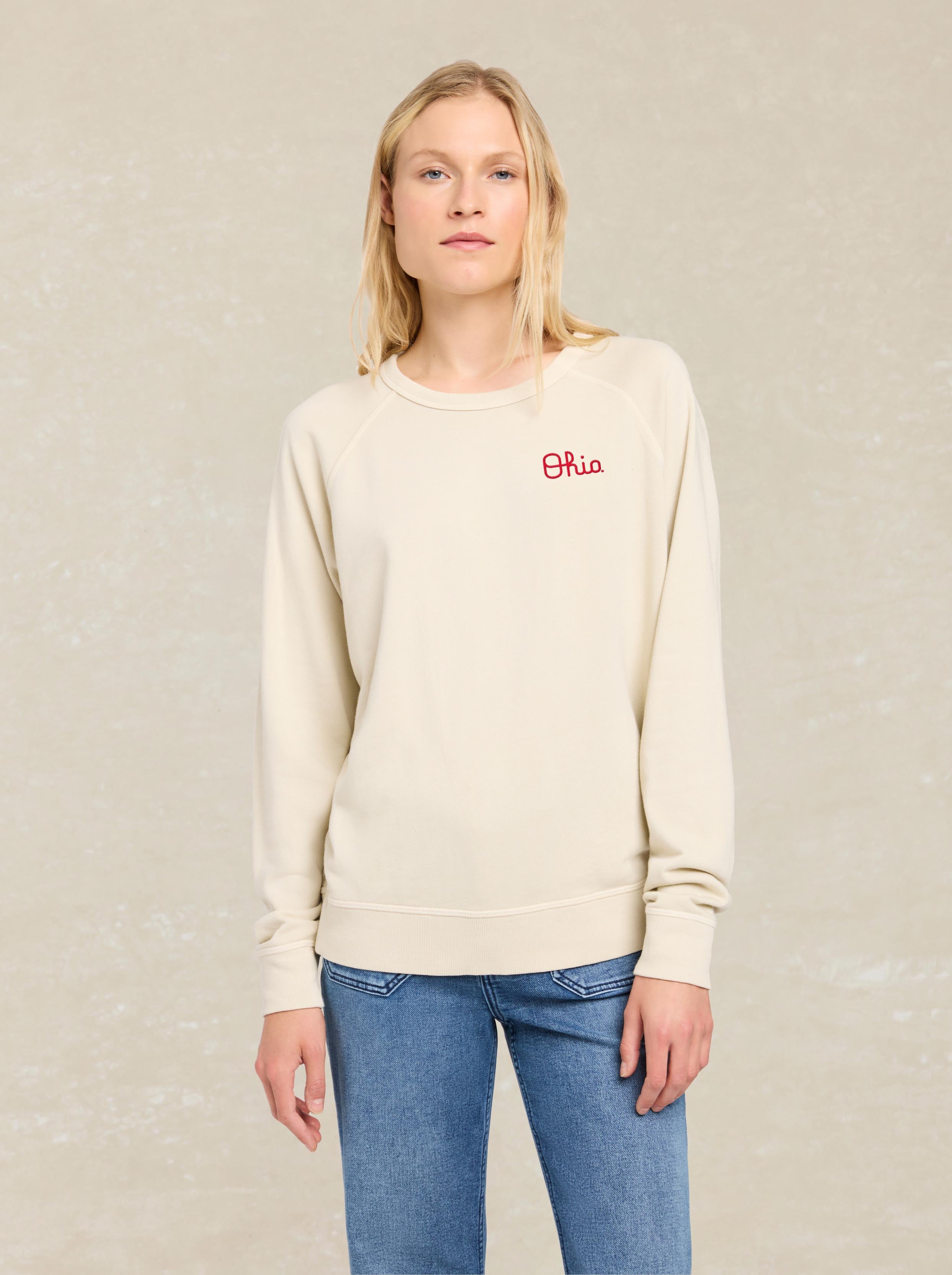 A woman wearing a white crewneck and blue jeans