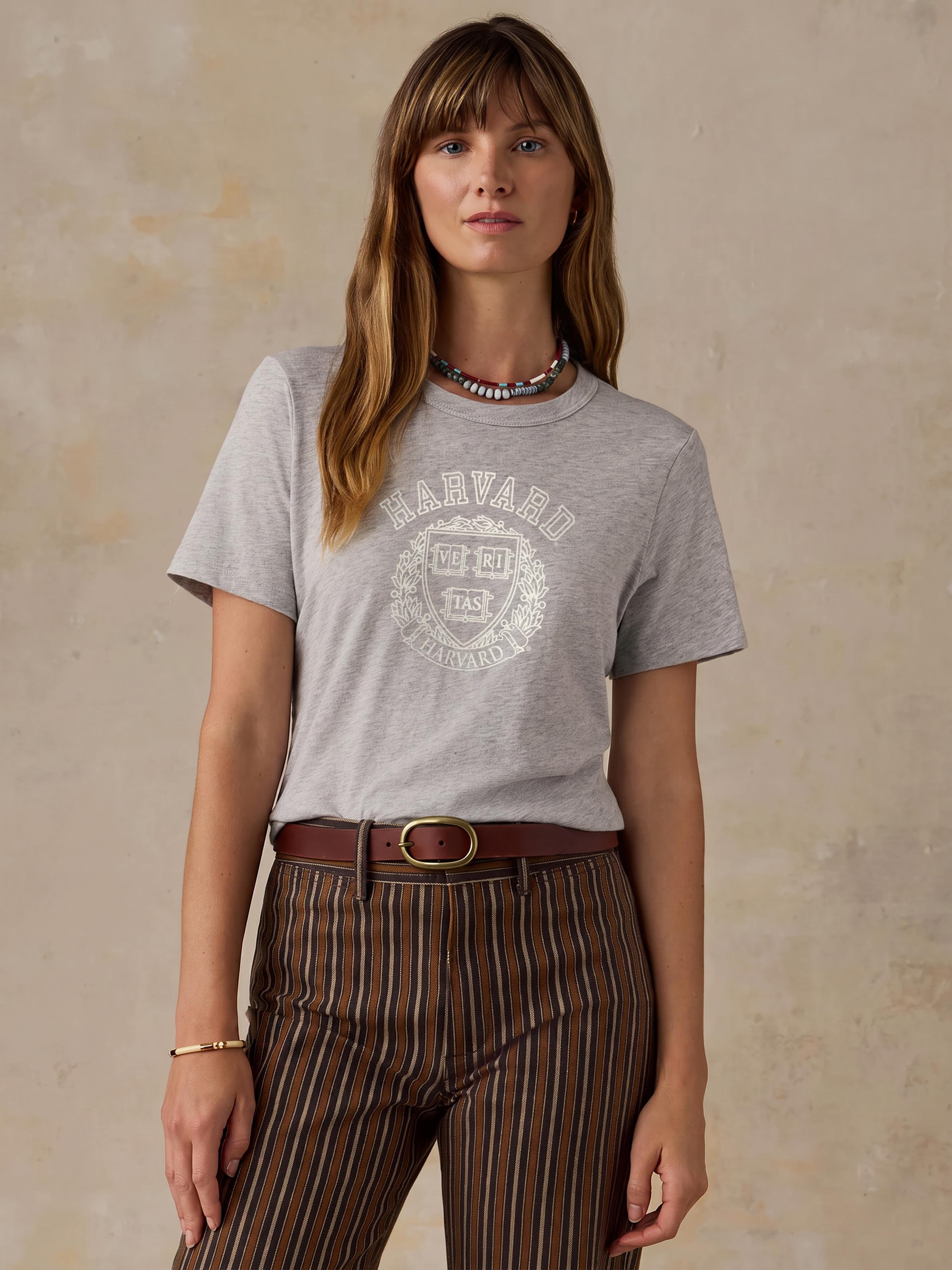 A woman wearing a grey harvard tee and brown striped pants