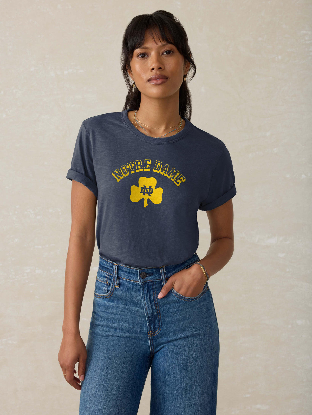 A woman wearing a blue Notre Dame tee and blue jeans, image 1 of 1