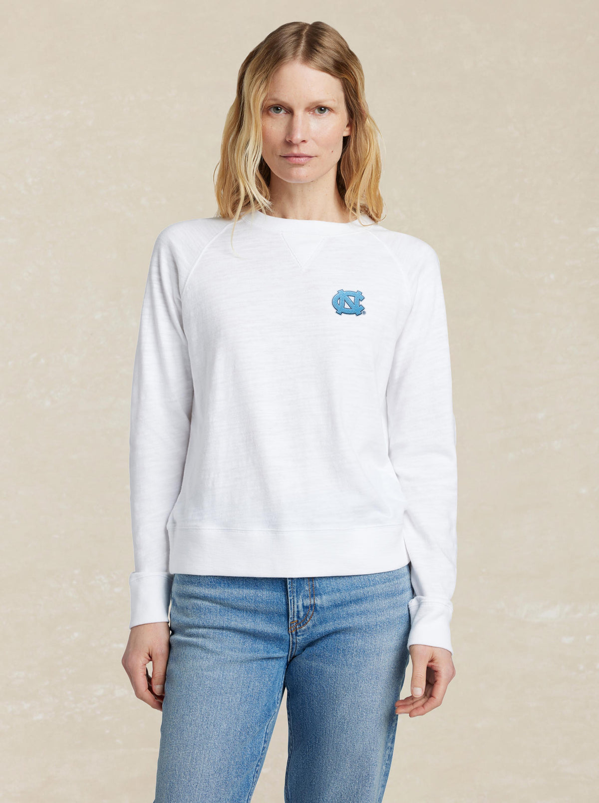A woman wearing a white University of North Carolina and blue jeans, image 1 of 1