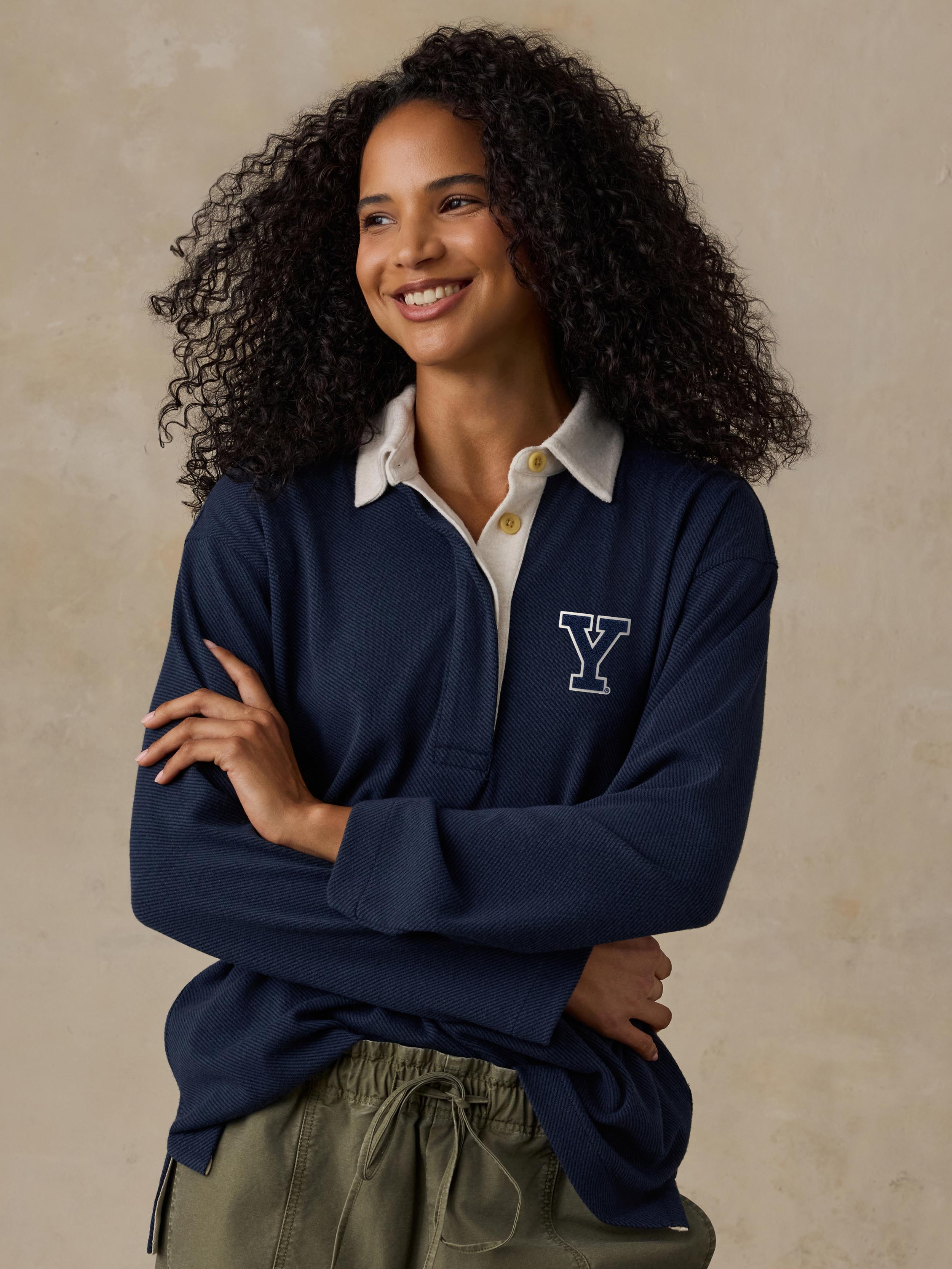 A woman wearing a blue Yale rugby shirt and green pants