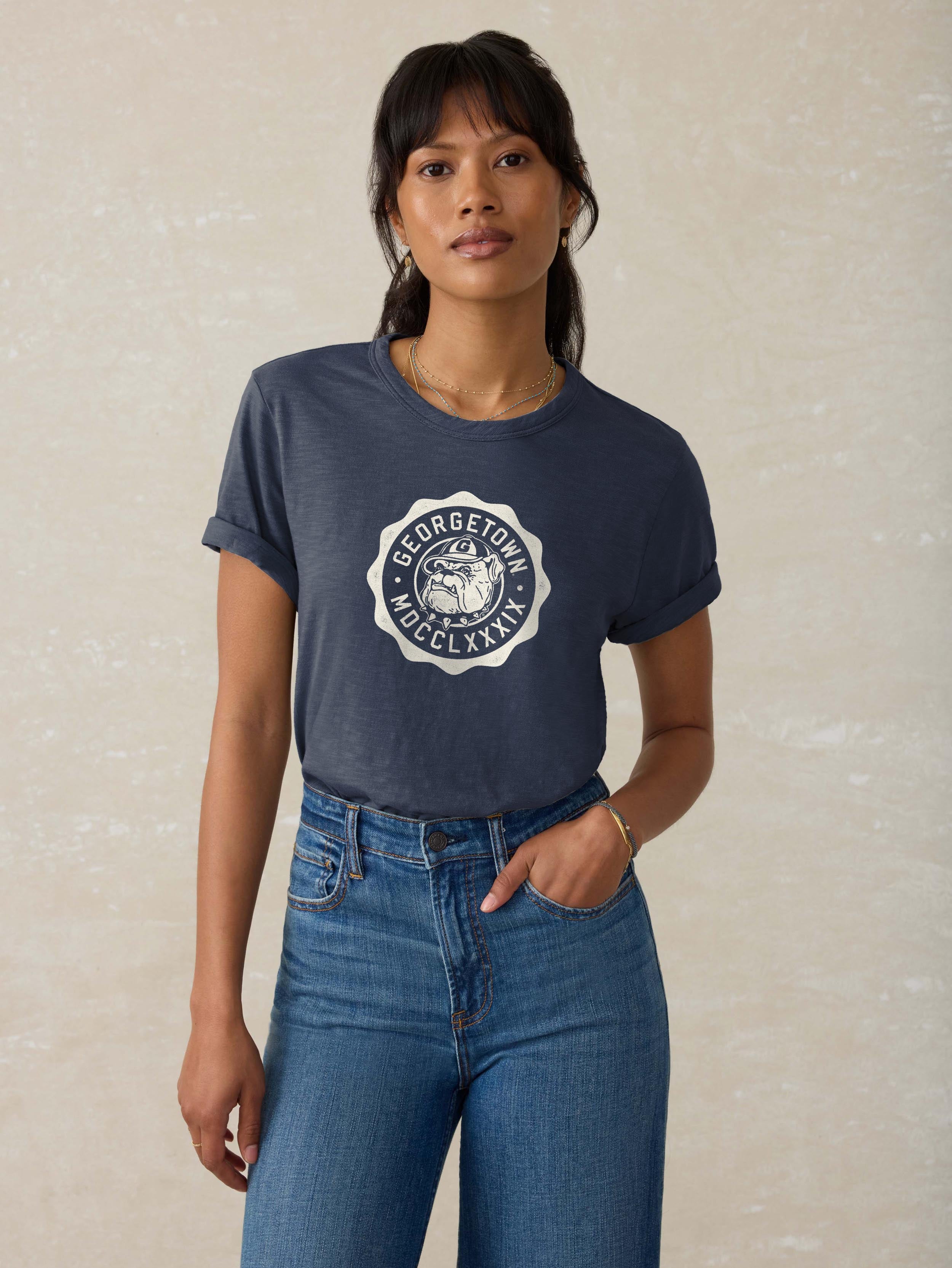 A woman wearing a blue Georgetown tee and blue jeans