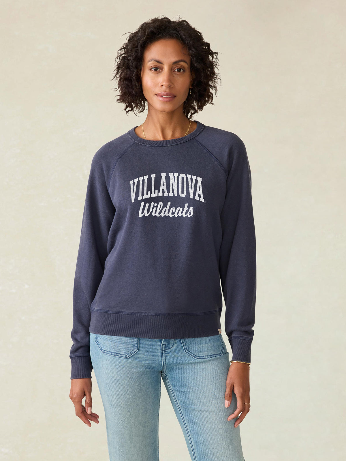 A woman wearing a blue Villanova crewneck and blue jeans, image 1 of 1